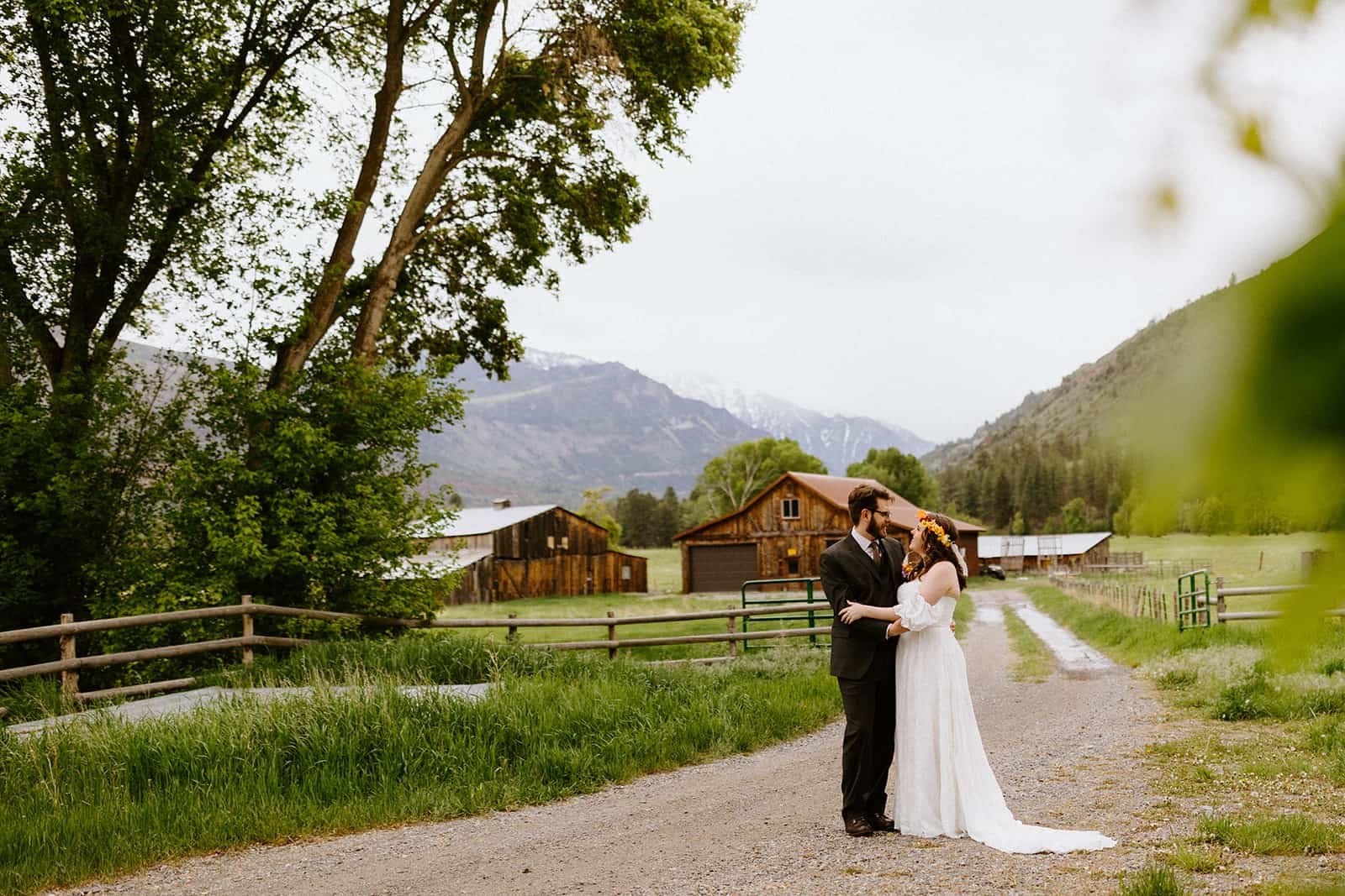 A man and woman in a wedding dress and suit embrace in front of Ouray Colorado