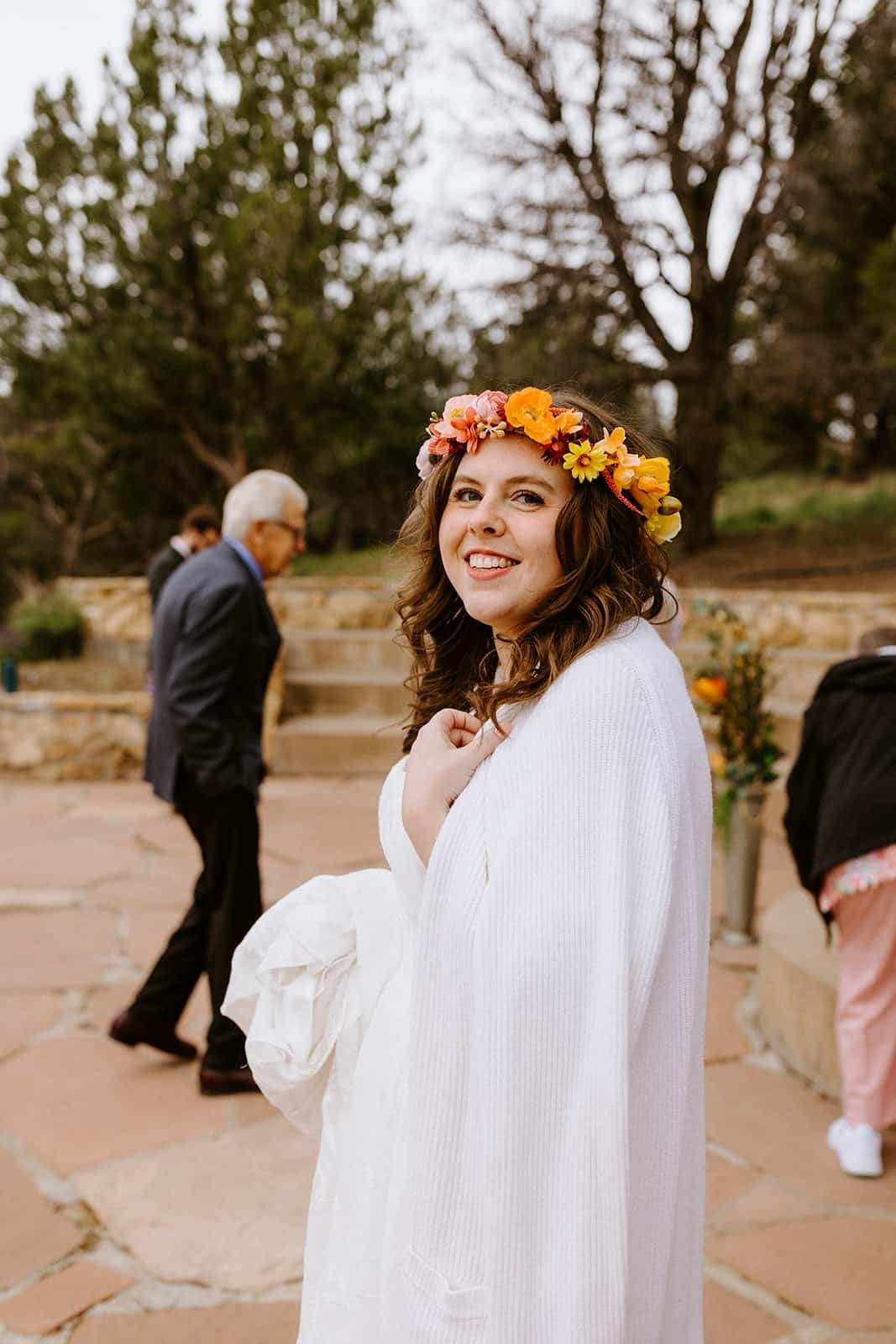A woman in a wedding dress and flower crown smiles