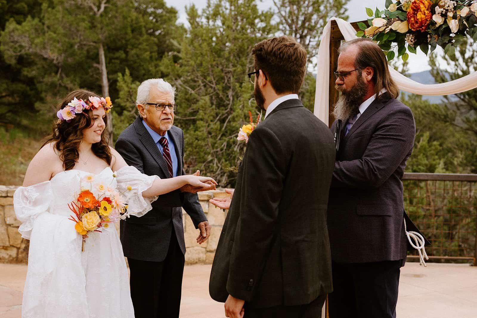 A father passes his daughters hand off to her new husband at the end of the aisle