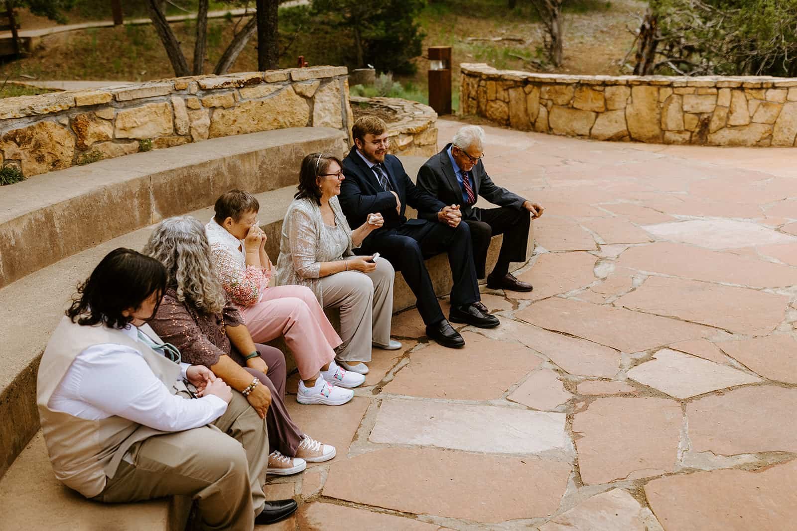 A family sits around on an amphitheater at Ridgway State Park for a wedding