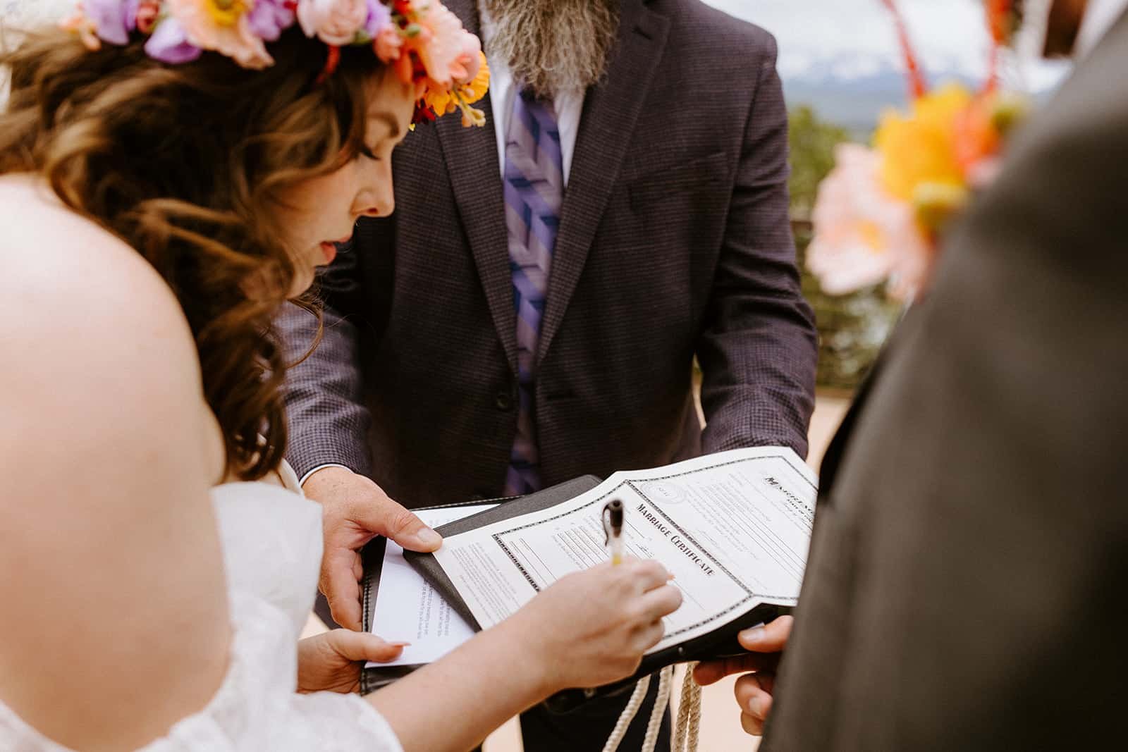 A couple signs their marriage license with their officiant in Colorado