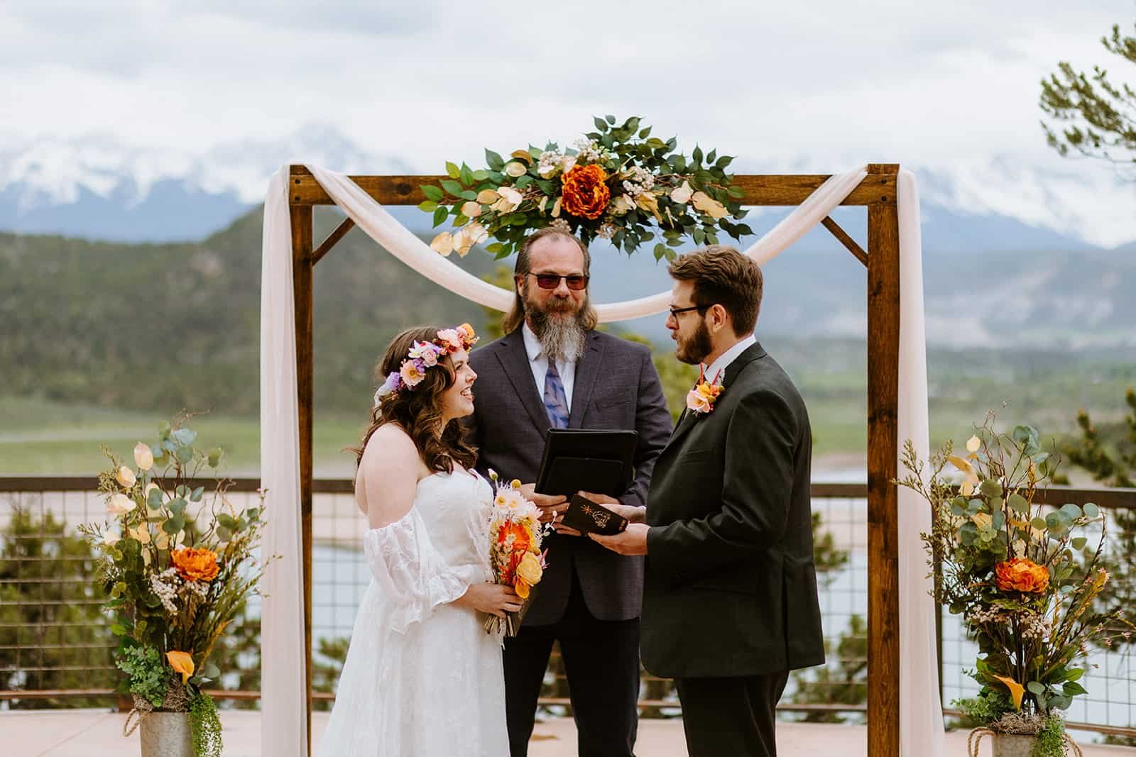 A man and woman stand in front of an arch at Ridgway State Park and the San Juan mountains in the background to get married