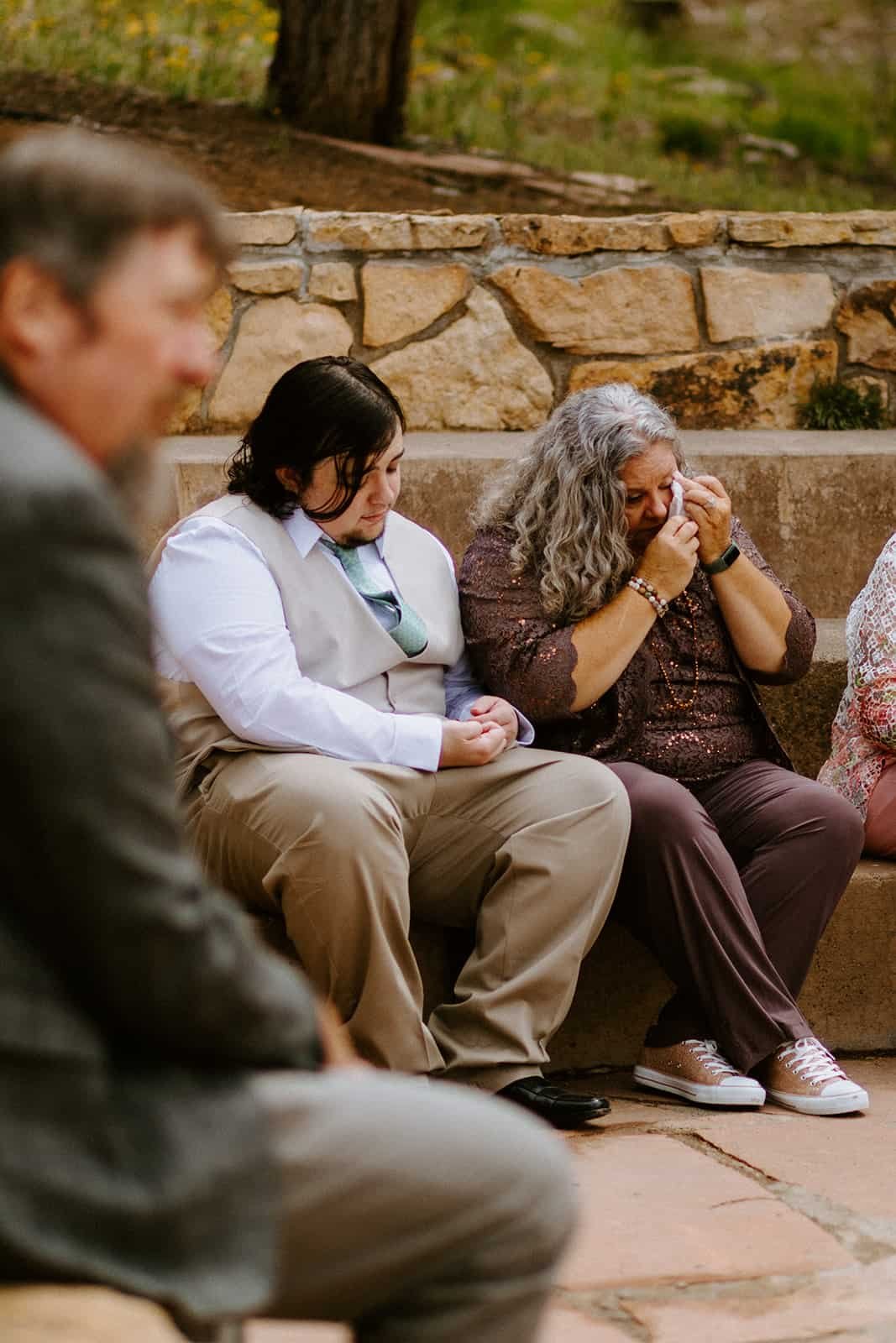 A family member wipes away emotional tears while looking on at a wedding ceremony
