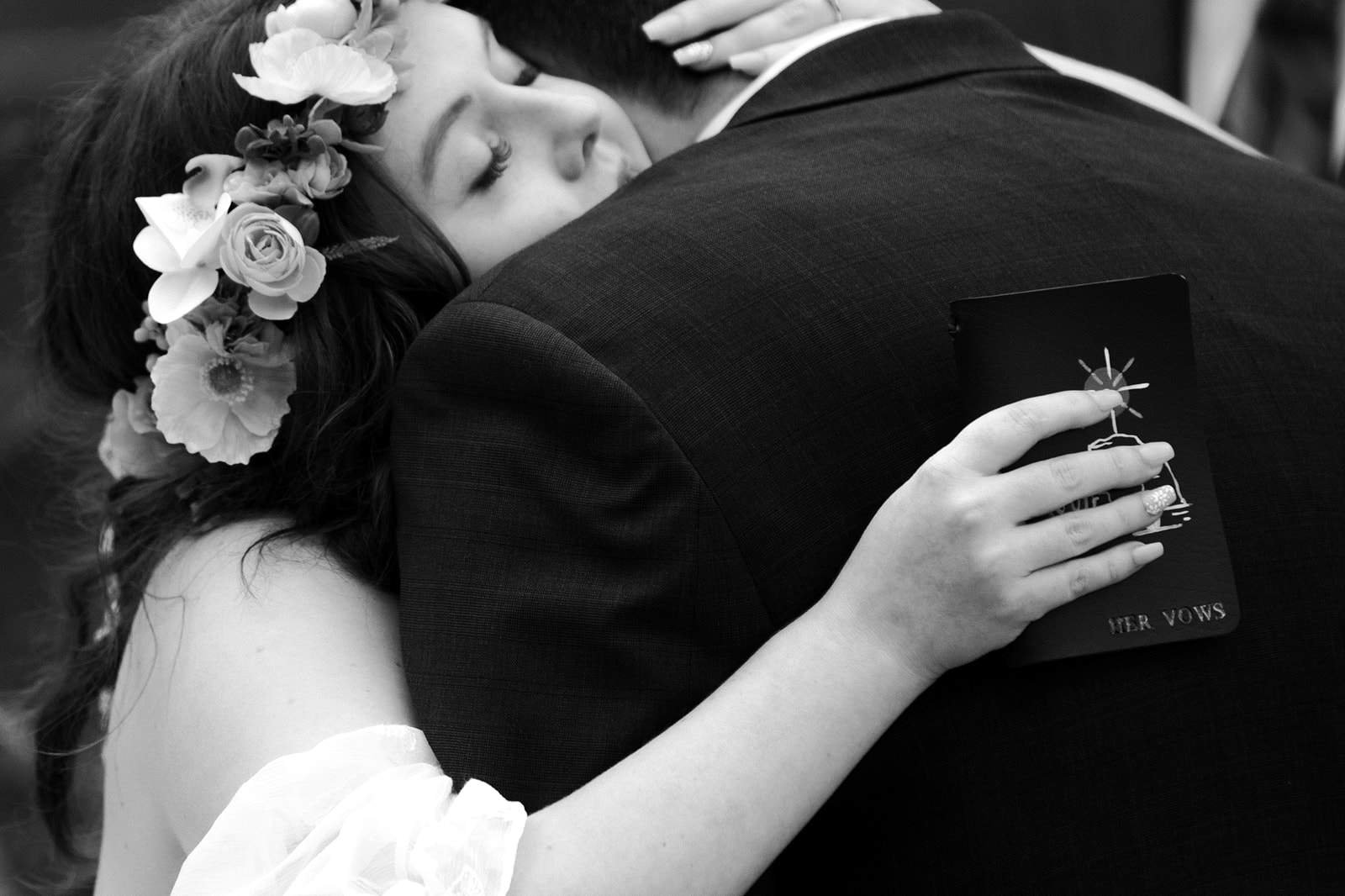 A woman in a wedding dress hugs a man in a suit