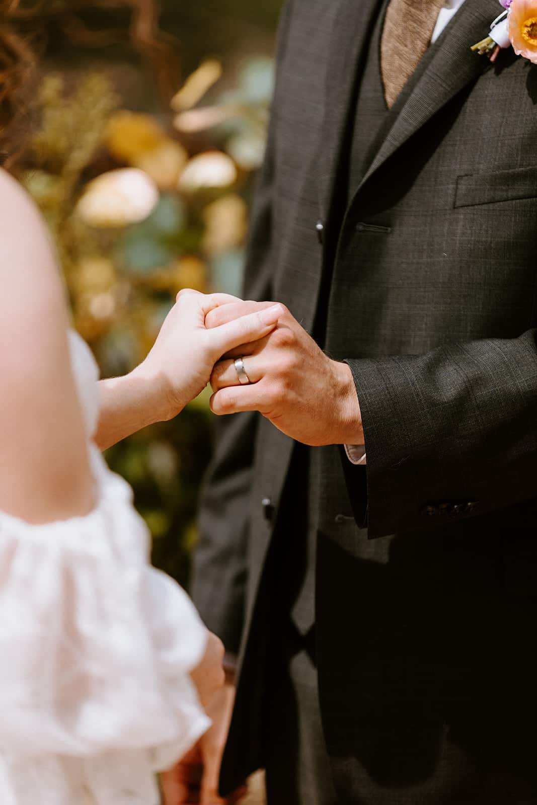 A couple holds hands during their wedding ceremony