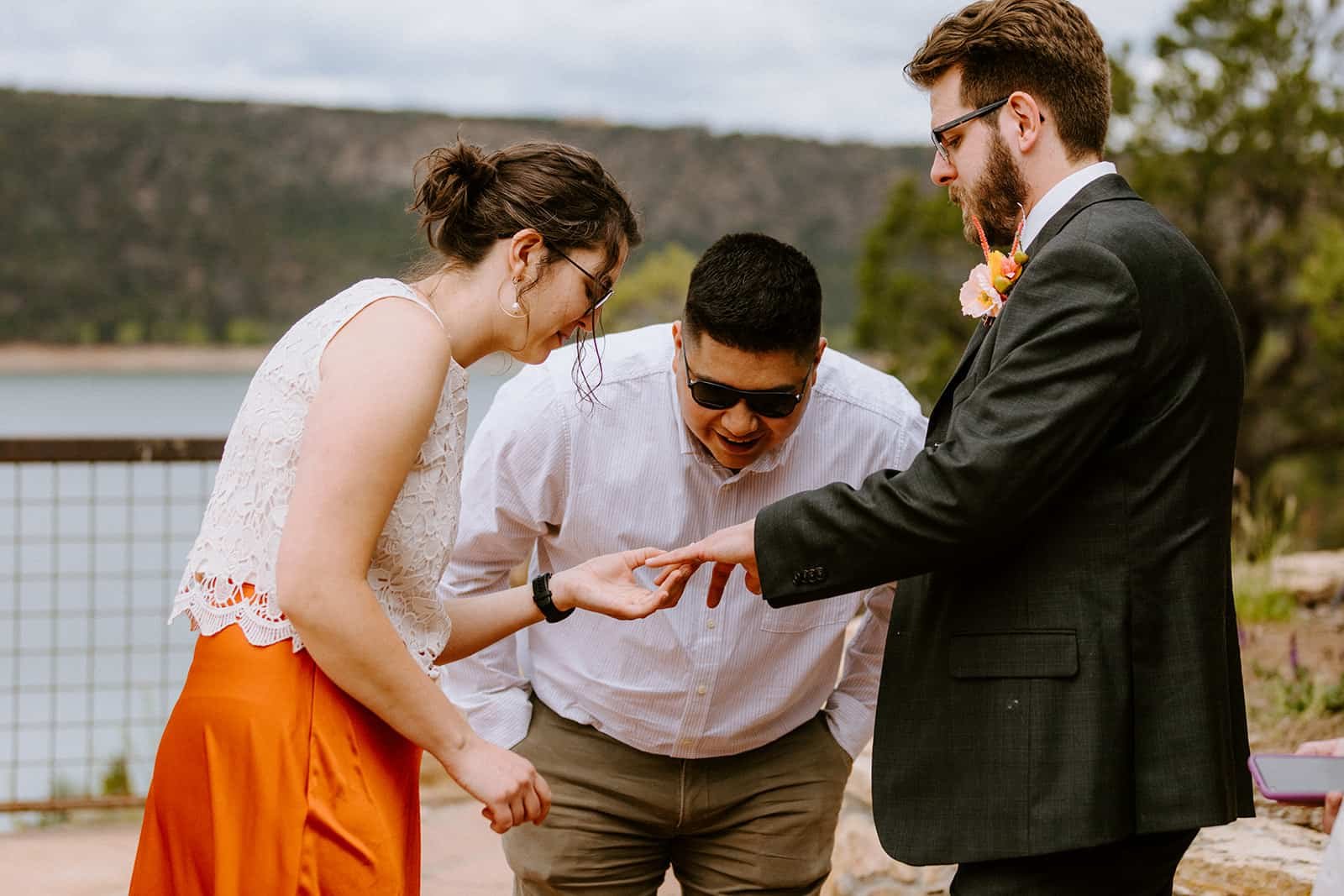 A man holds out his hand for two friends to see his new wedding ring