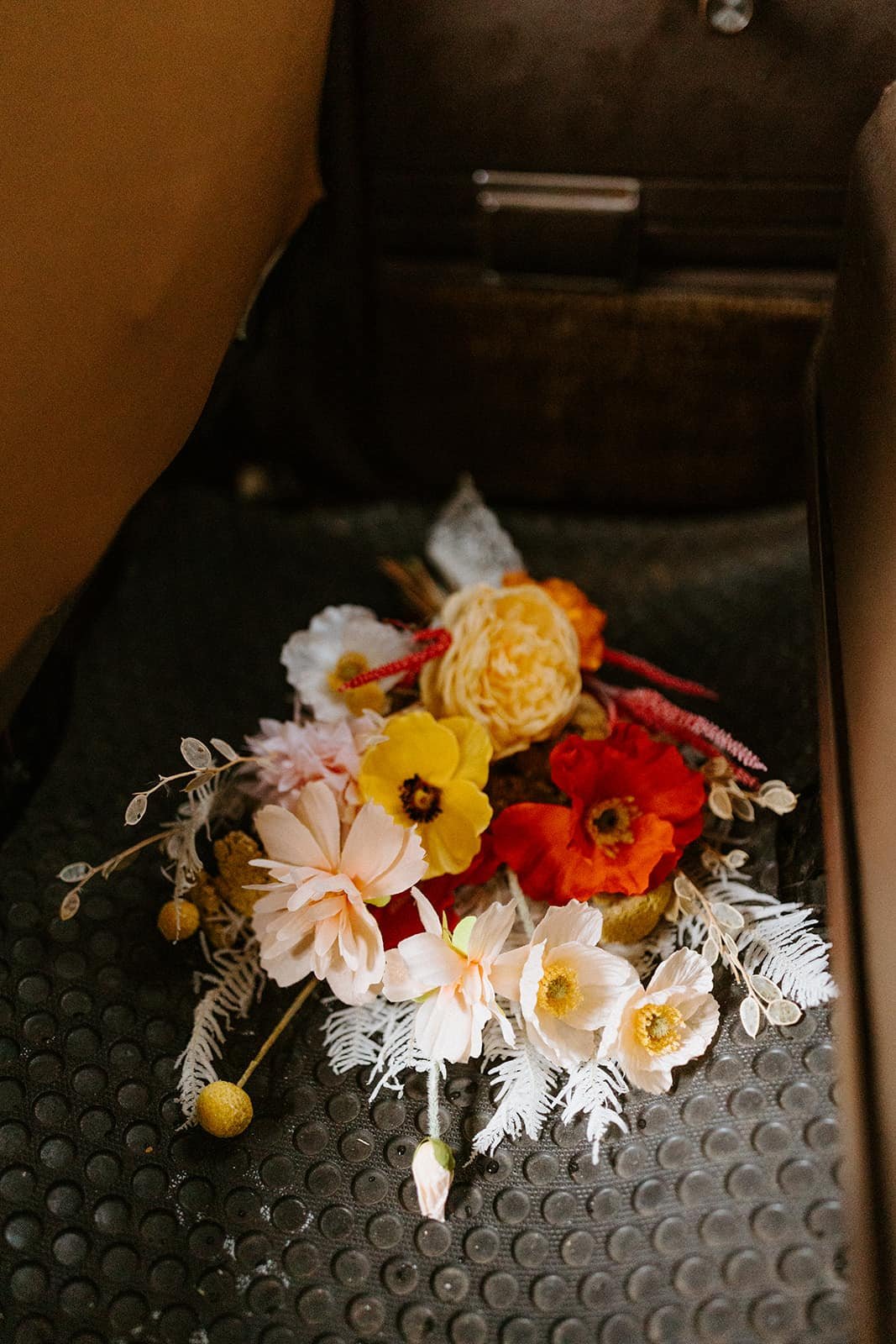 A bouquet of flowers sits on the floor of a car