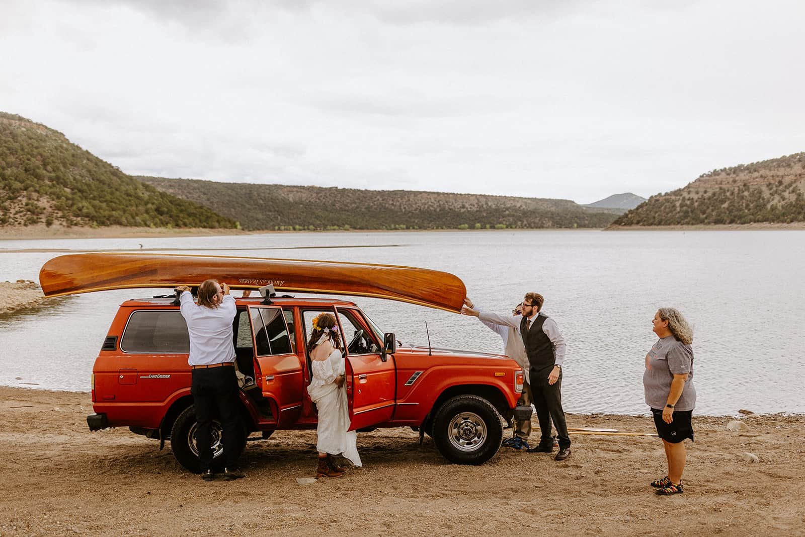 A family helps put a wood canoe on the roof of a Land Cruiser car