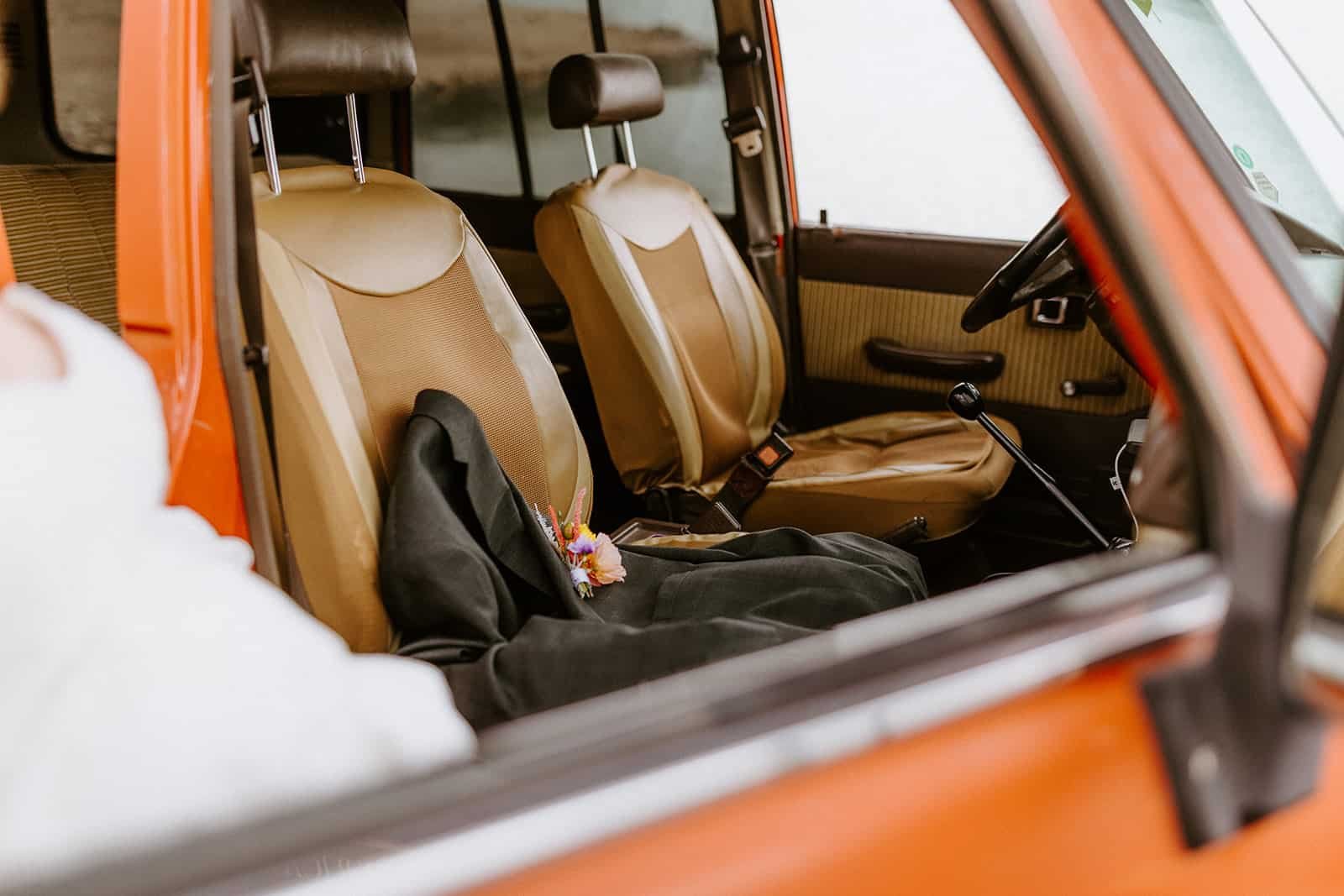 A suit jacket sits on tan leather seats of a Toyota Land Cruiser through a window that is down