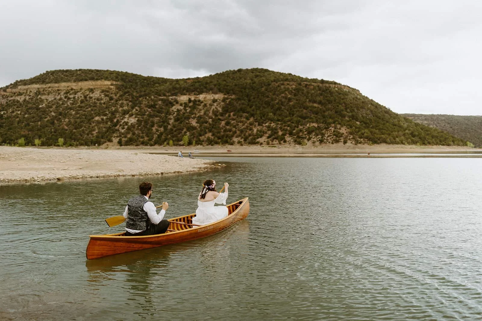 Bride and groom in a wooden rowboat on a scenic lake at Ridgway State Park near Ouray, Colorado
