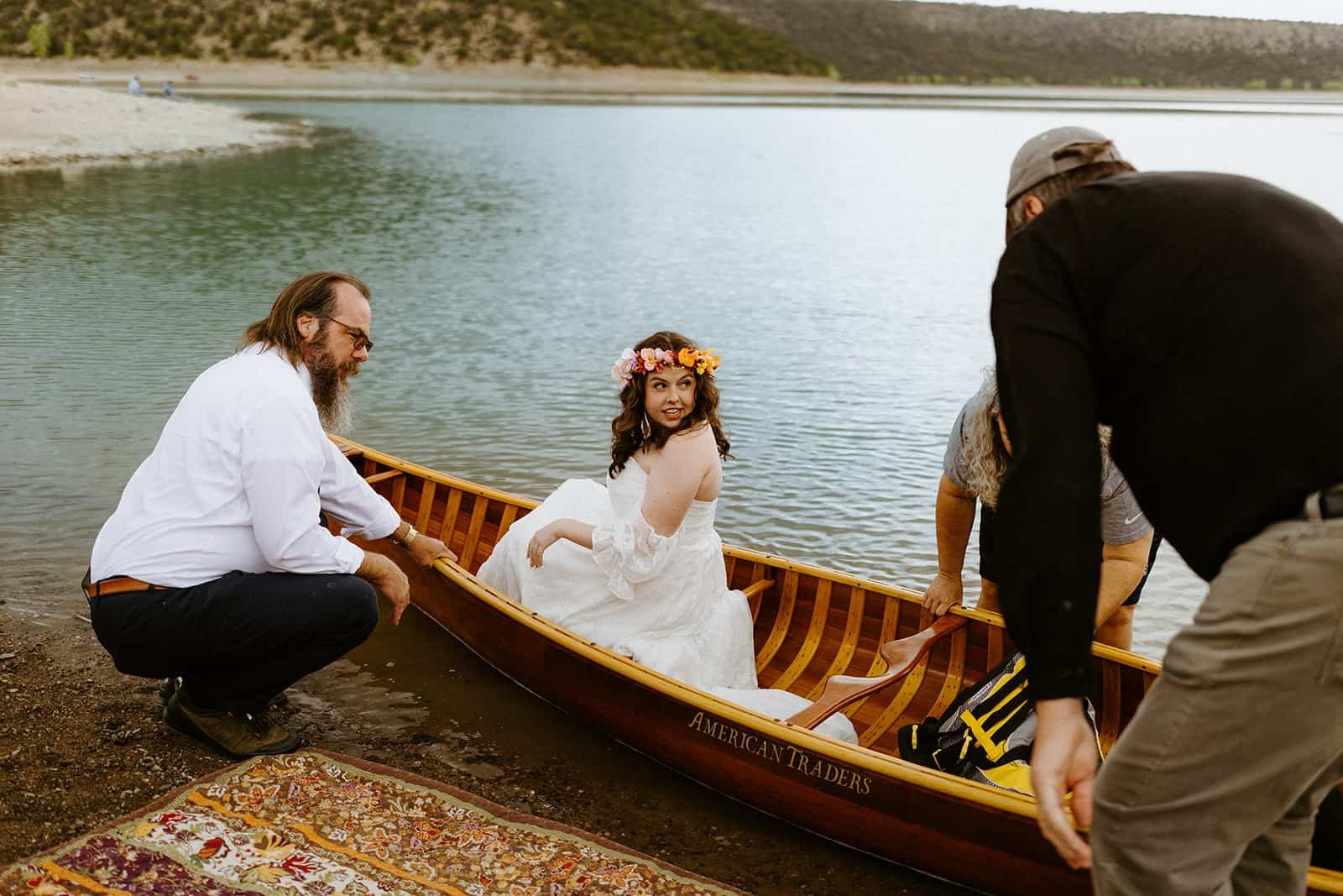 A family helps a couple get into a wood canoe