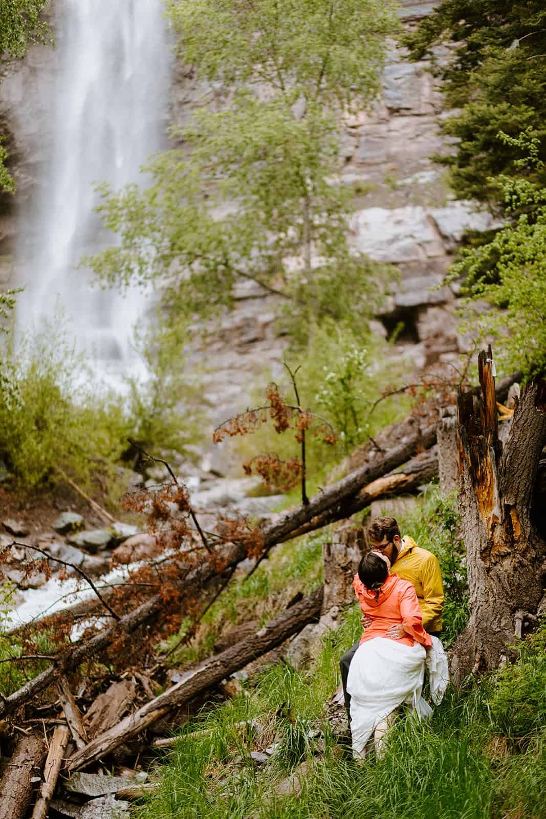 A couple embraces in front of a waterfall in Colorado