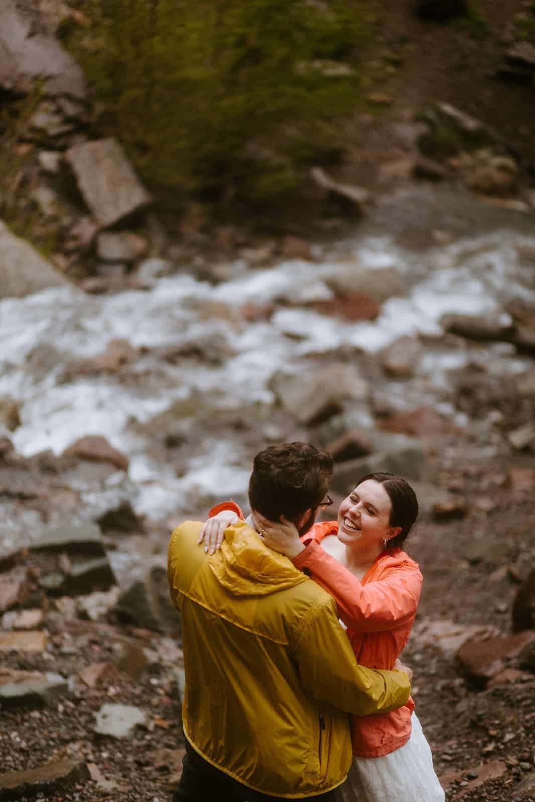 A couple in rain jackets smiles at each other