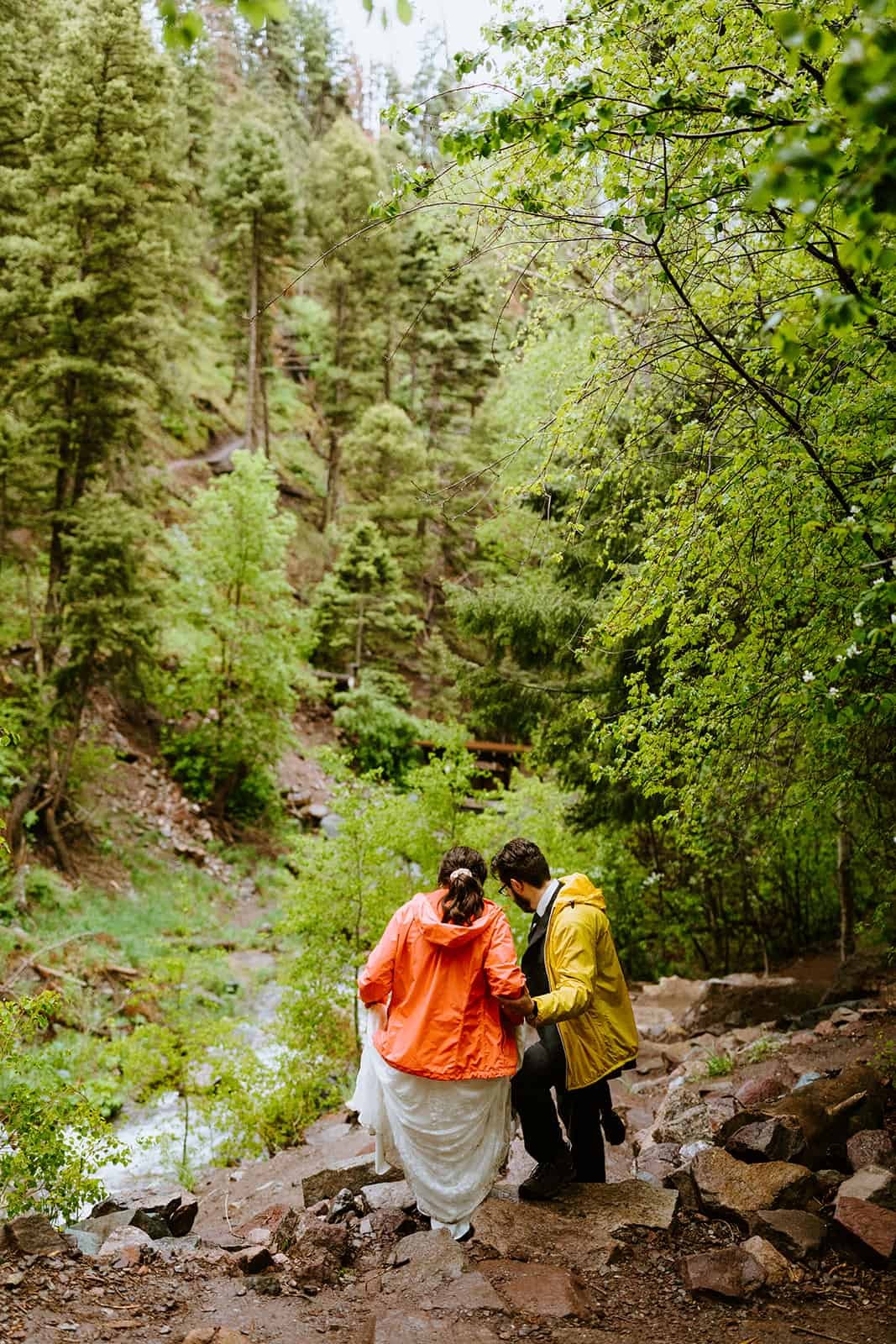 A man helps a woman walk down a rocky trail in the San Juan mountains