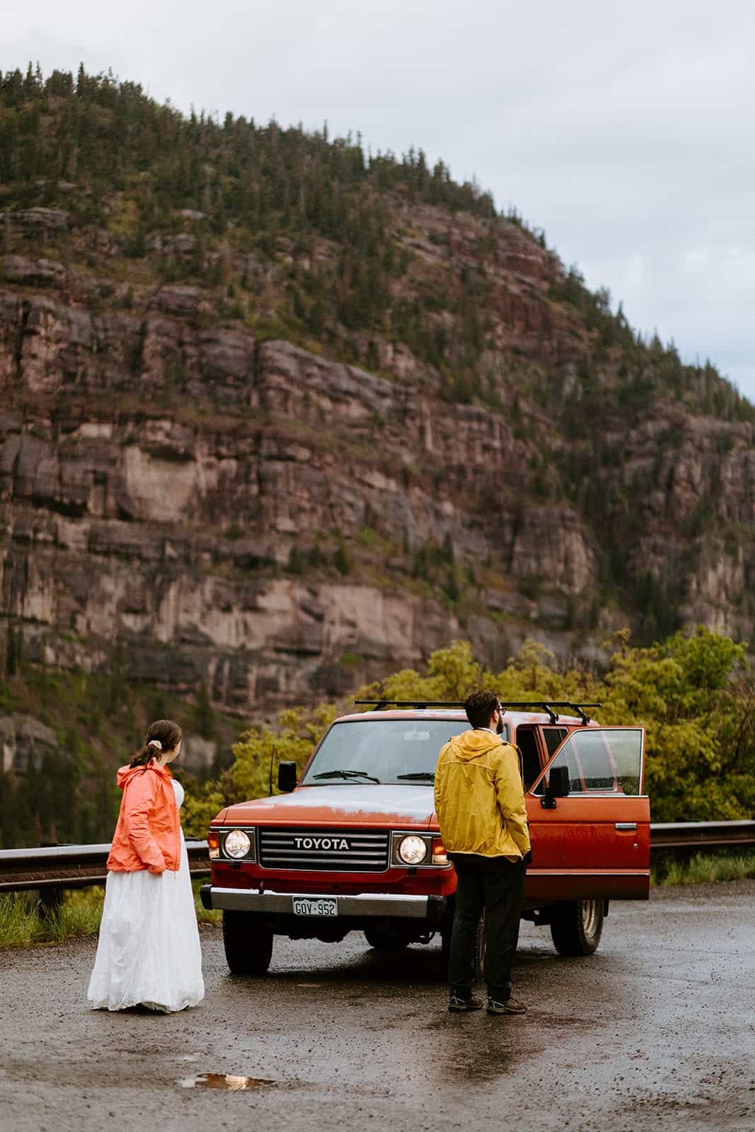 A couple stands in their wedding clothes on a pull out on the million dollar highway