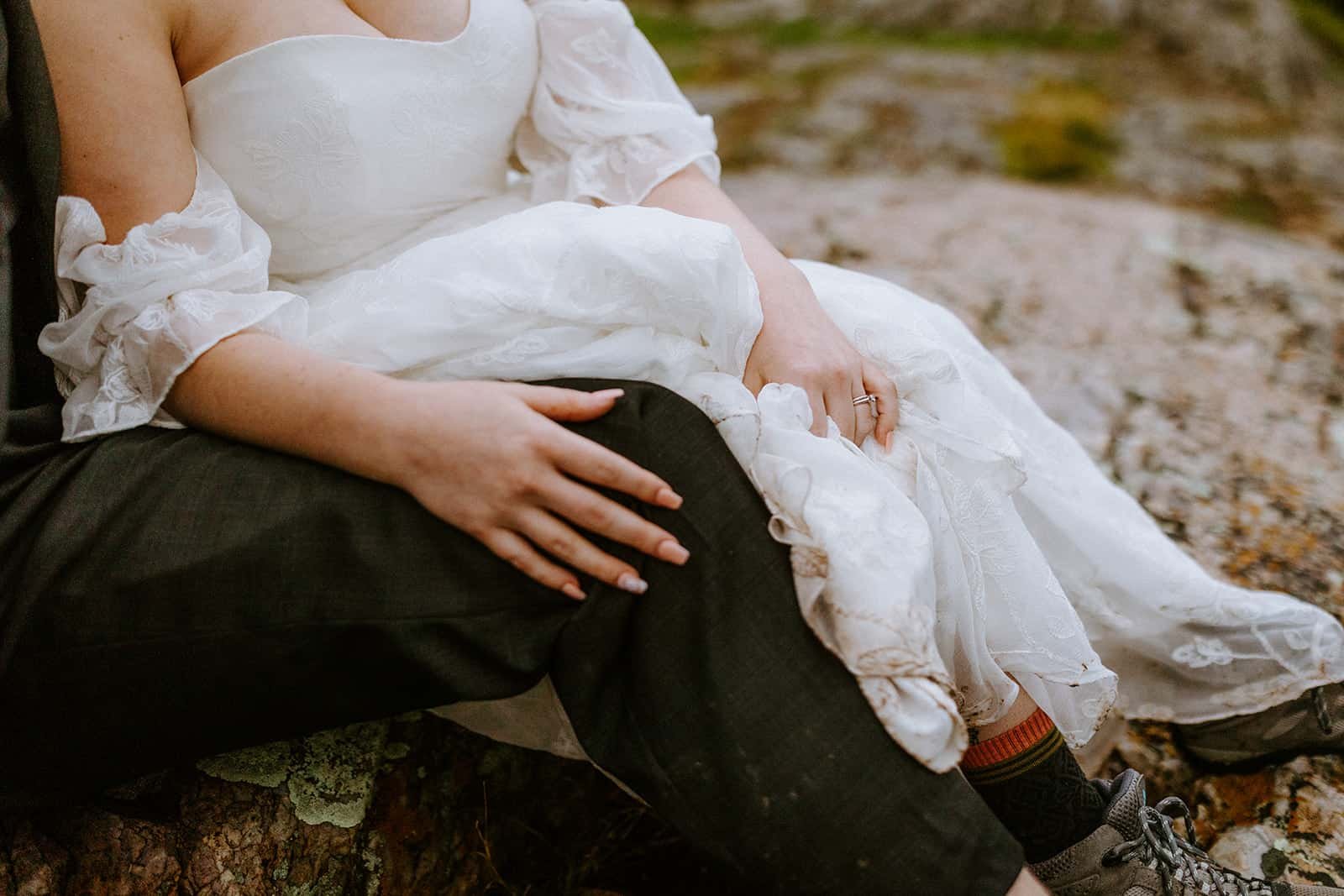 A woman in a wedding dress places her hand on her partners knee