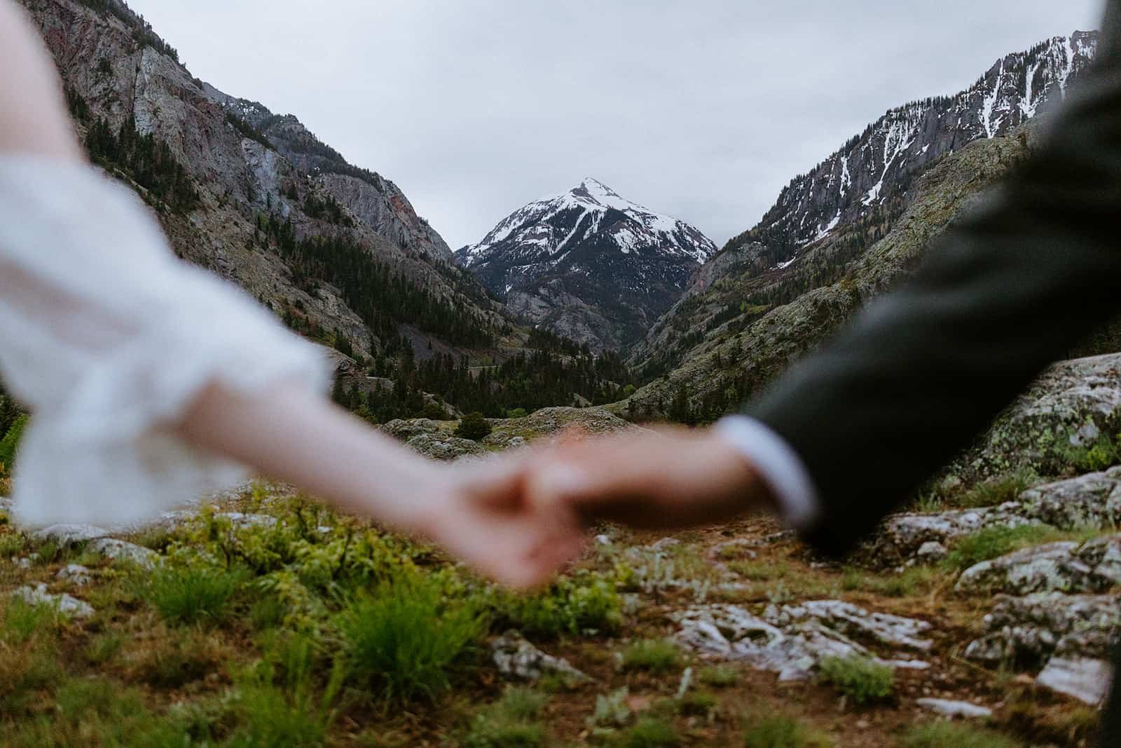 A mountain range behind a couple holding hands