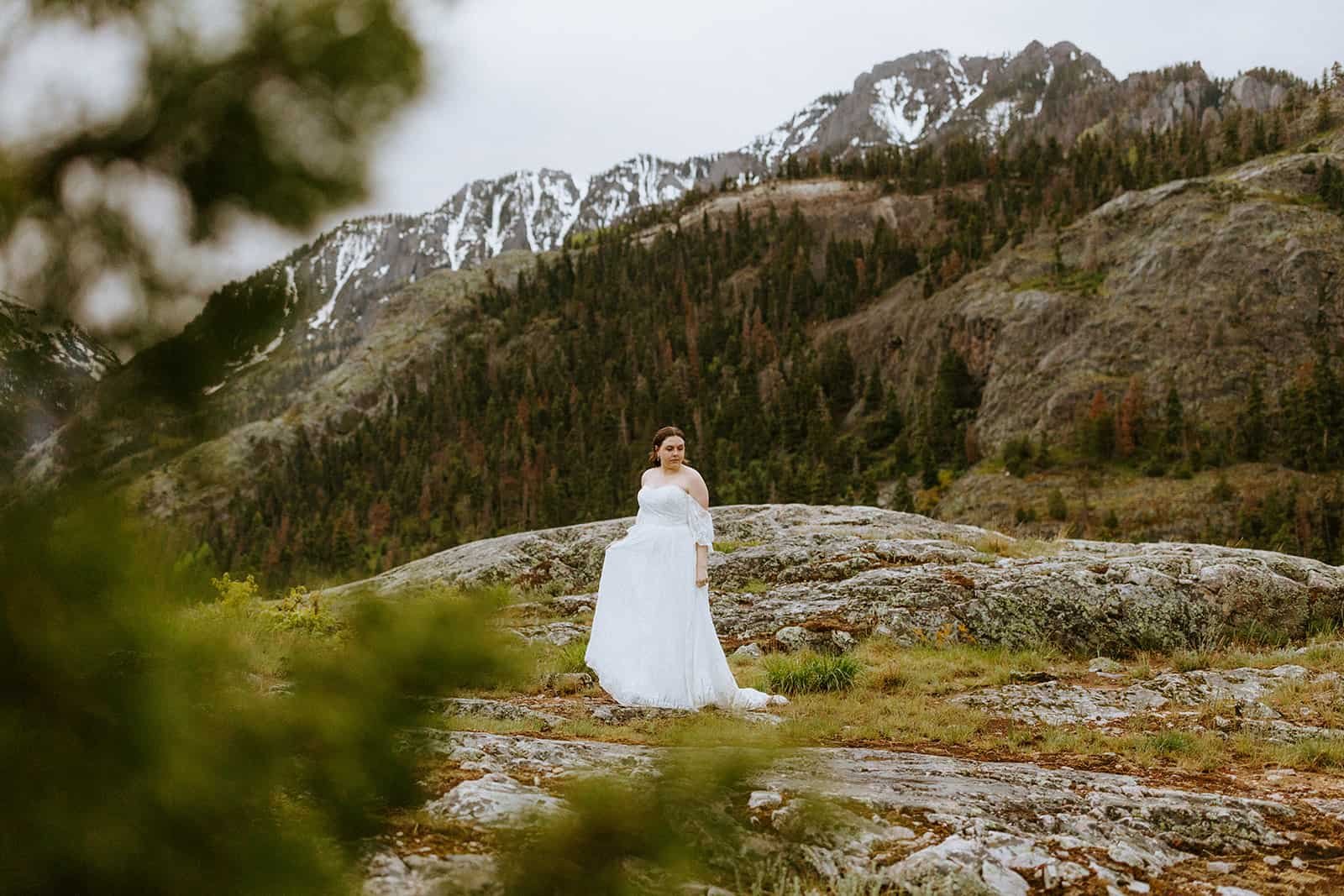 A woman twirls in her wedding dress in front of mountains