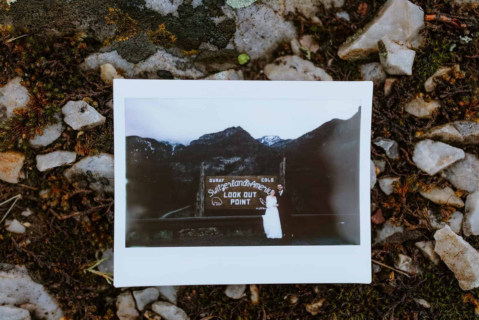 A polaroid of a couple at the Switzerland of America sign against rock