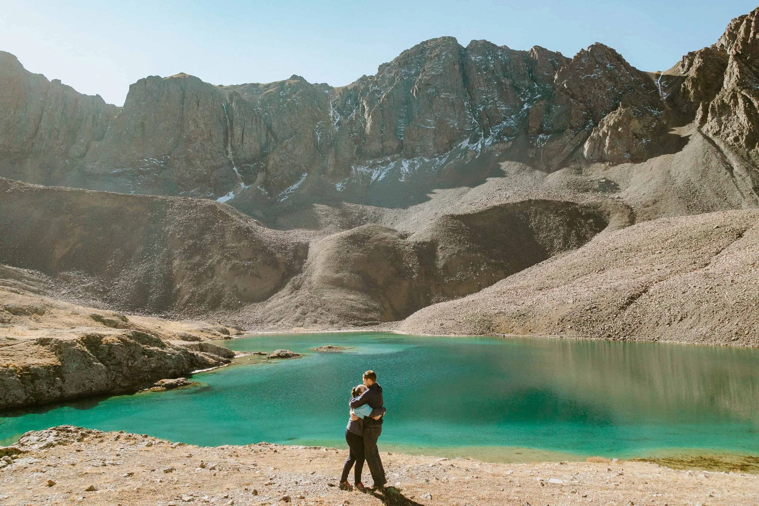 Couple beside a turquoise alpine lake under rocky cliffs, one of the most private places to elope near Lake City