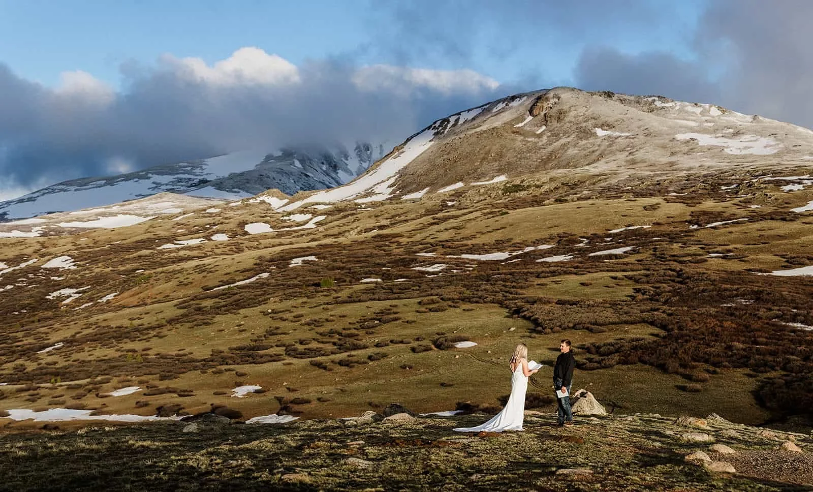 Bride and groom on rocky mountain terrain near Georgetown, Colorado with snow patches and Guanella Pass views