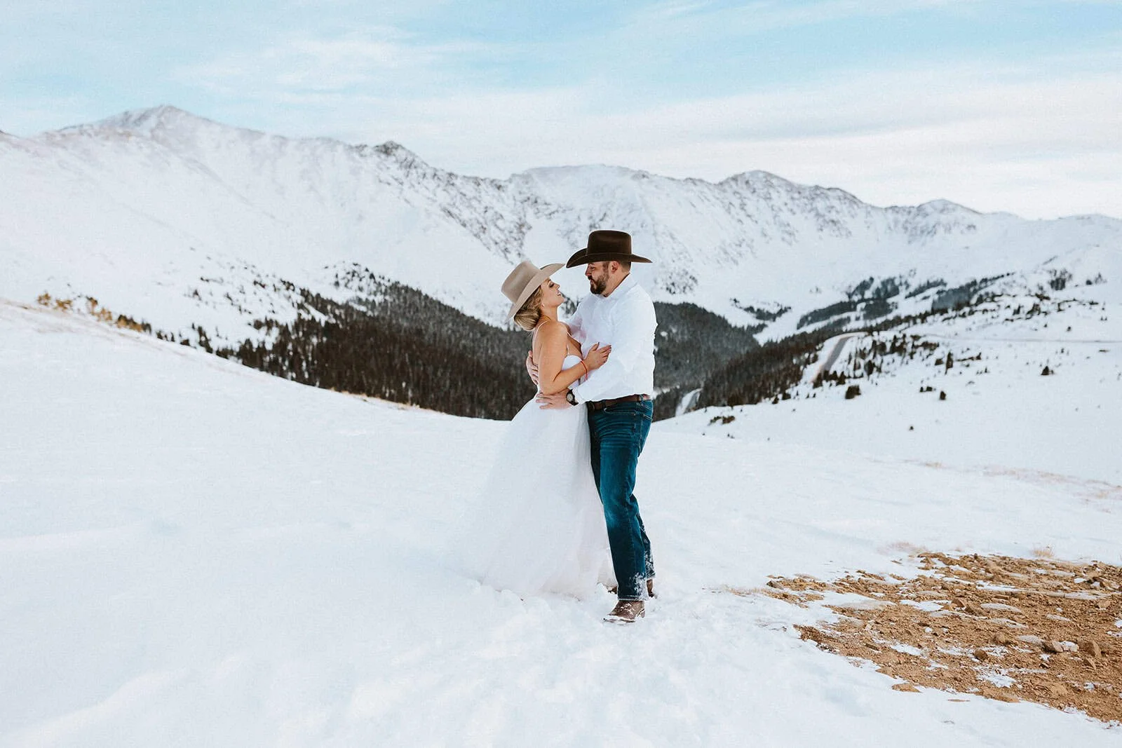 A bride and groom in cowboy hats get married on top of Loveland Pass in the winter