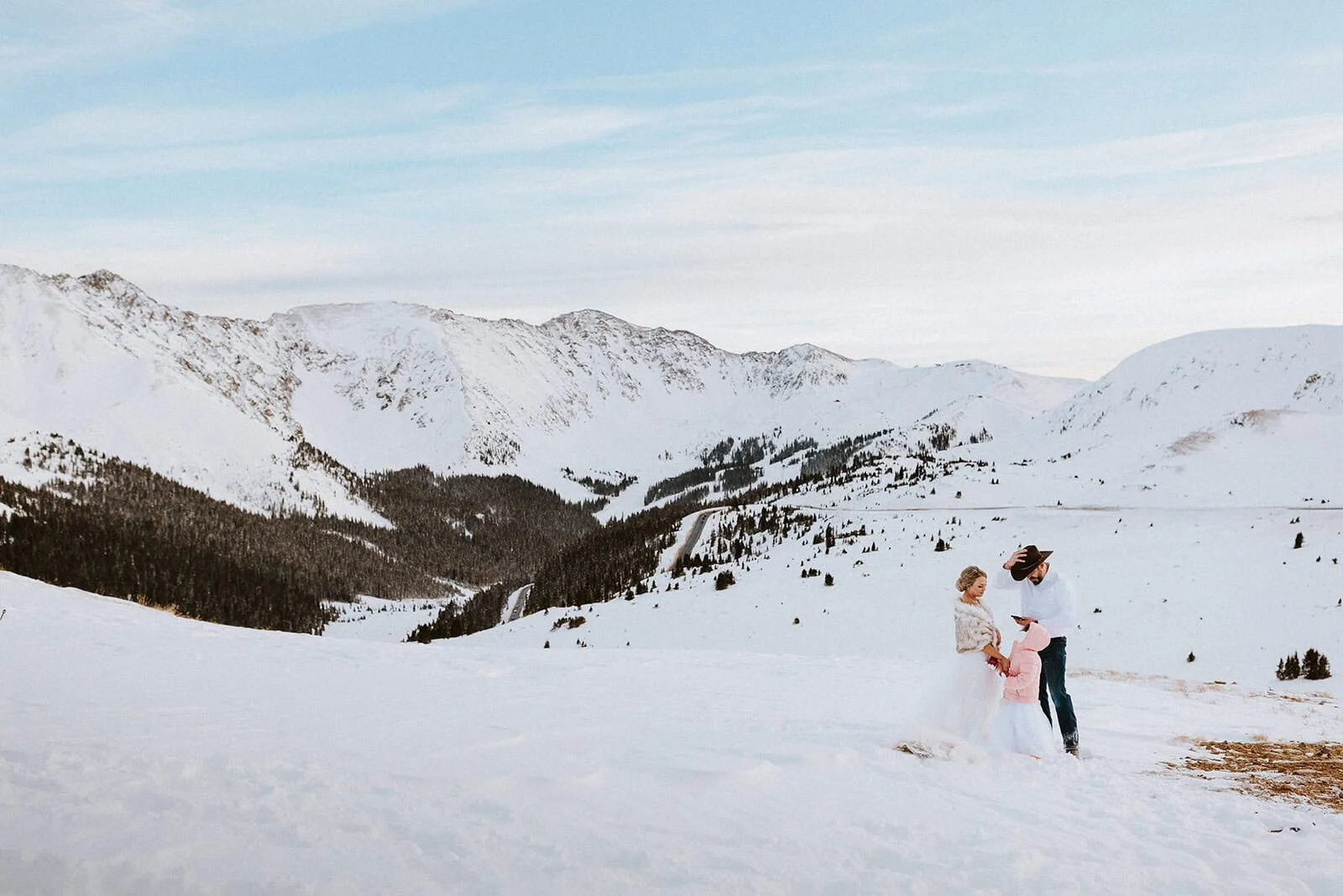 A couple stands in deep snow on Loveland Pass with snow covered mountains behind them