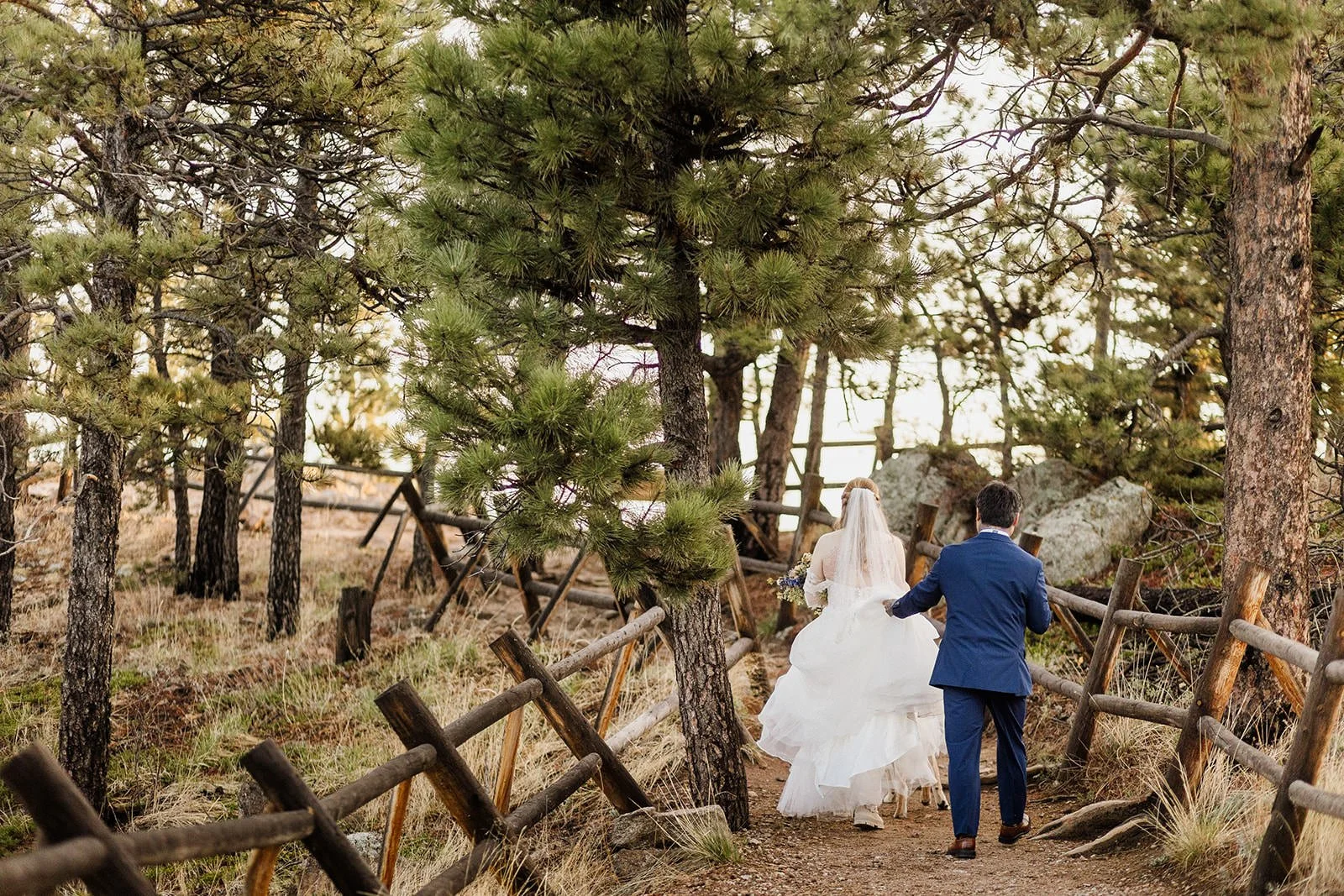 Couple walking down the fenced path to Lost Gulch Overlook in their wedding clothes