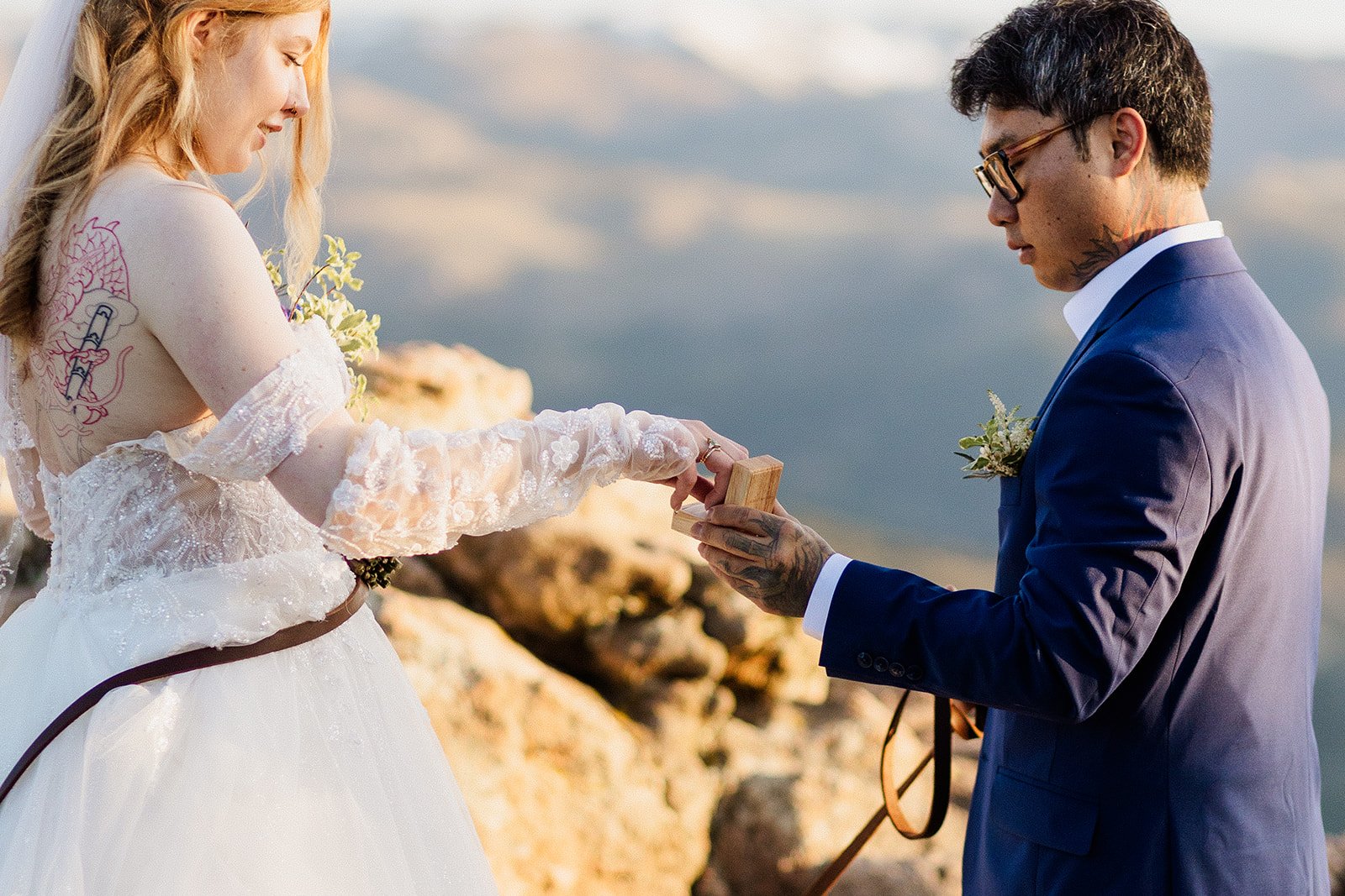 Groom opening a ring box as the bride reaches toward it