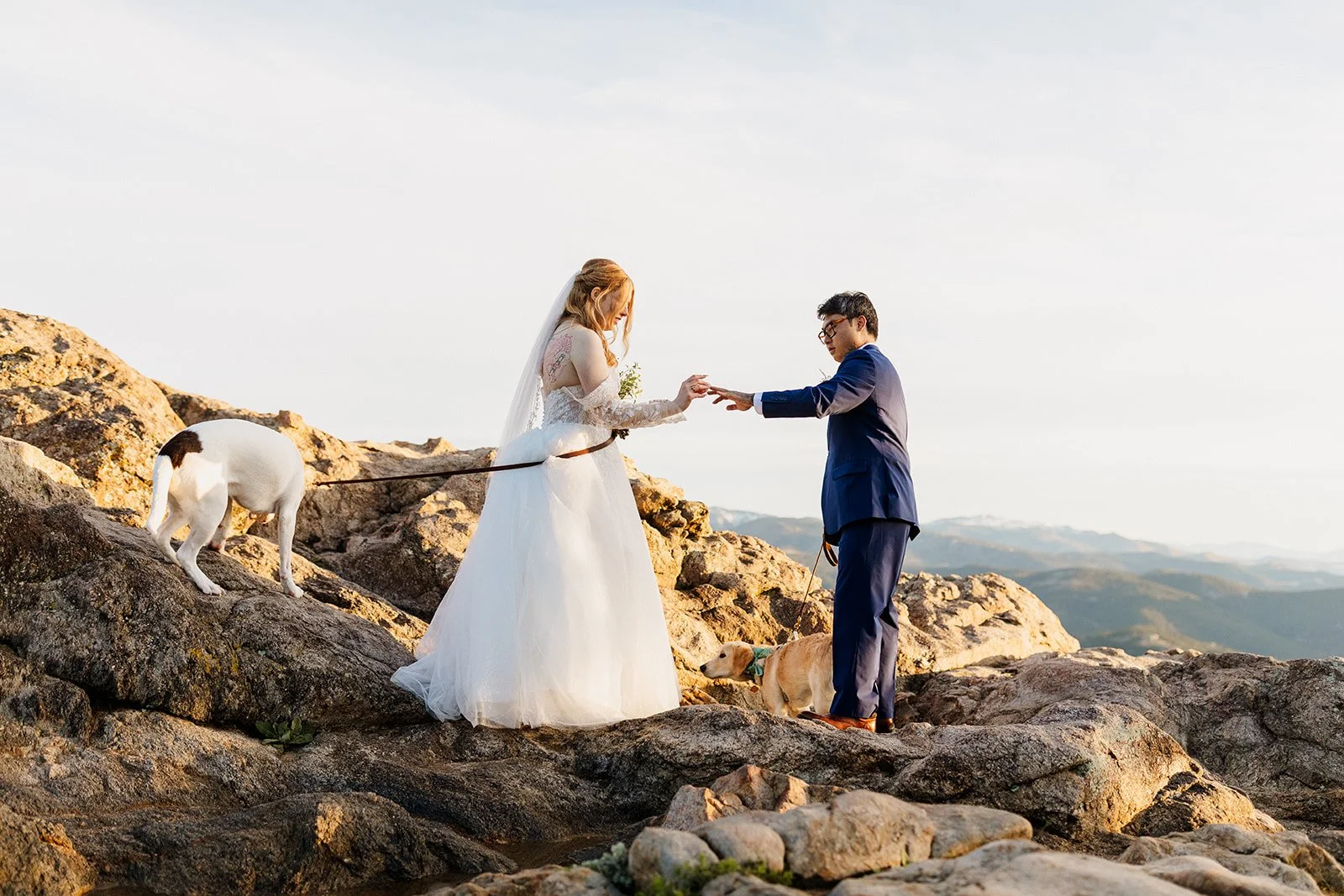 Couple exchanging rings on the rocks at Lost Gulch Overlook while their dog sniffs around behind them