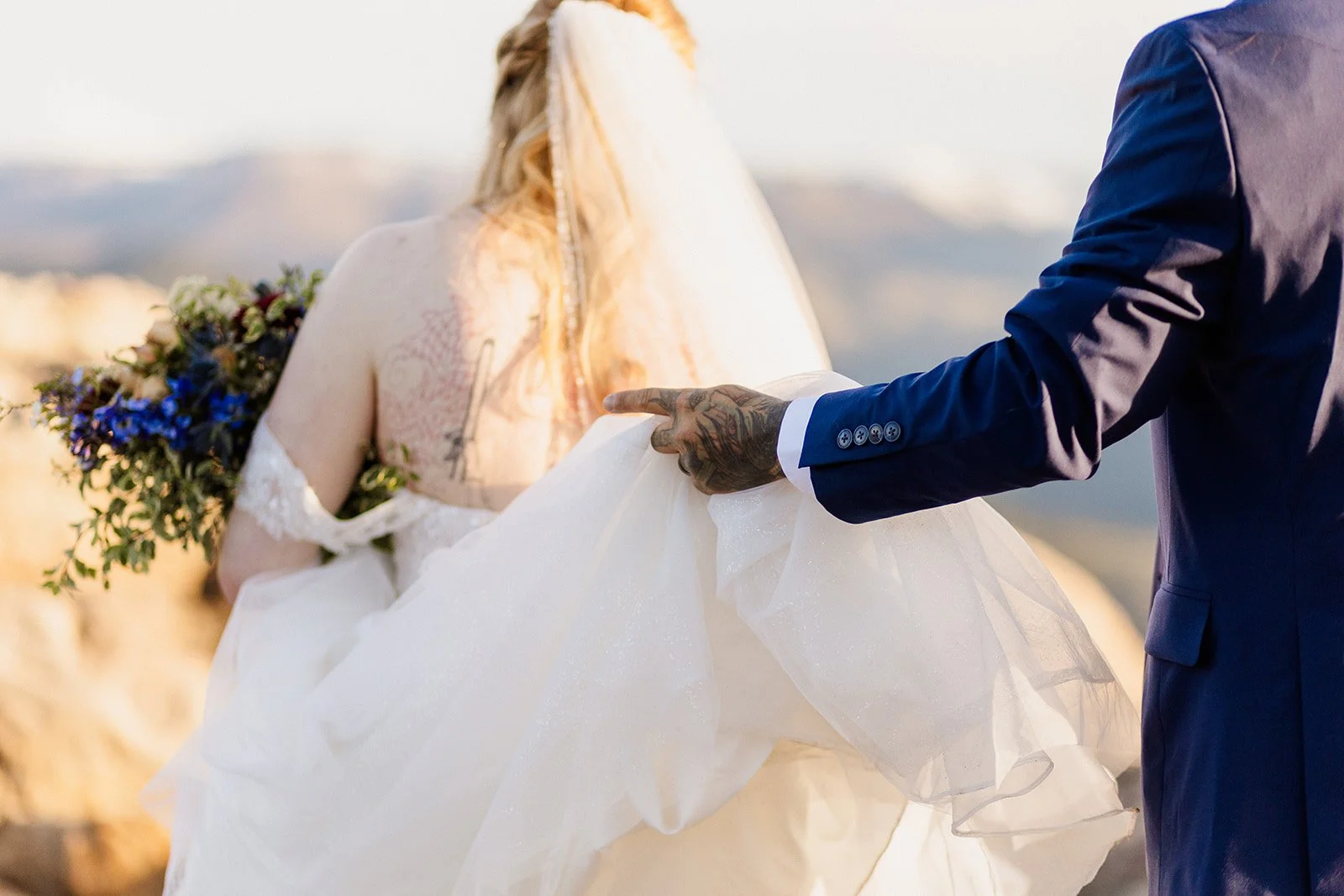 Groom lifting the train of the bride's dress as they walk