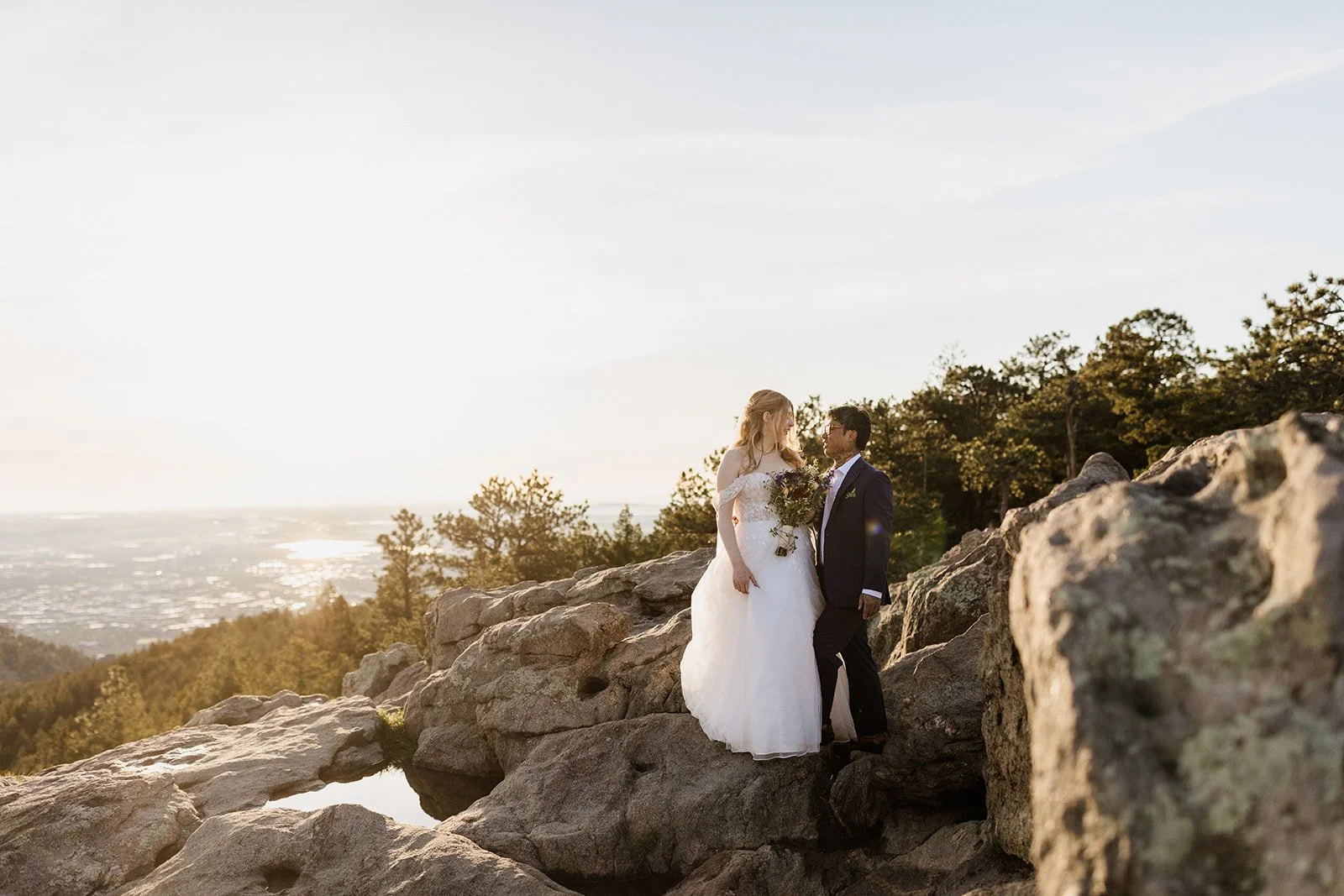 Couple standing on a rock ledge in soft morning light with the plains in the distance