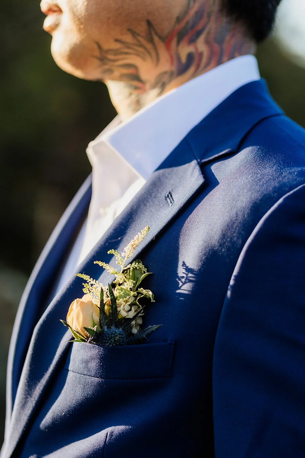 Close up of the groom's boutonniere and neck tattoo