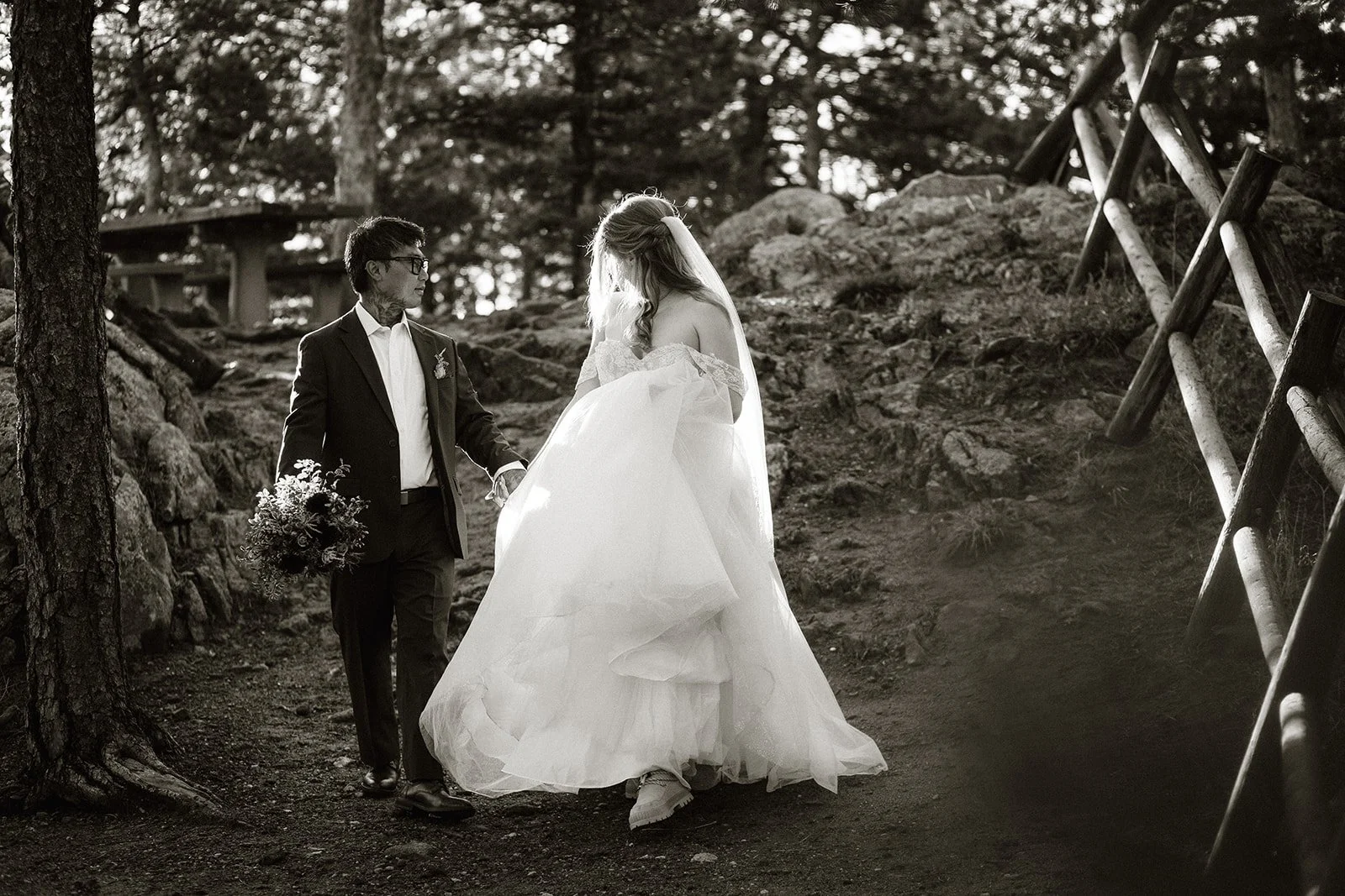 Couple walking hand in hand through the trees, in black and white