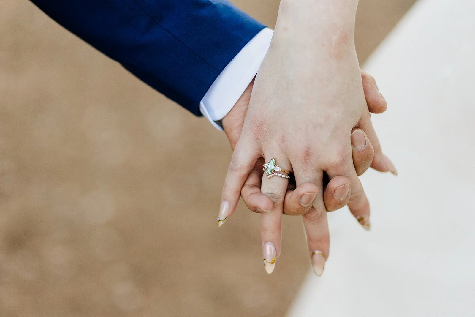 Close up of the couple holding hands, showing her engagement ring