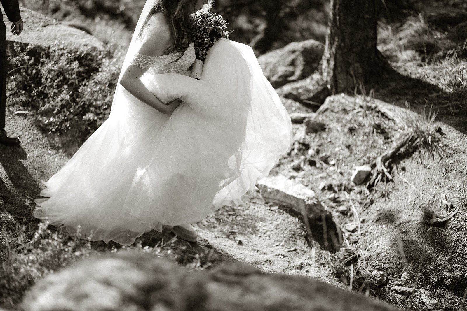 Black and white photo of the bride's dress sweeping over the rocks