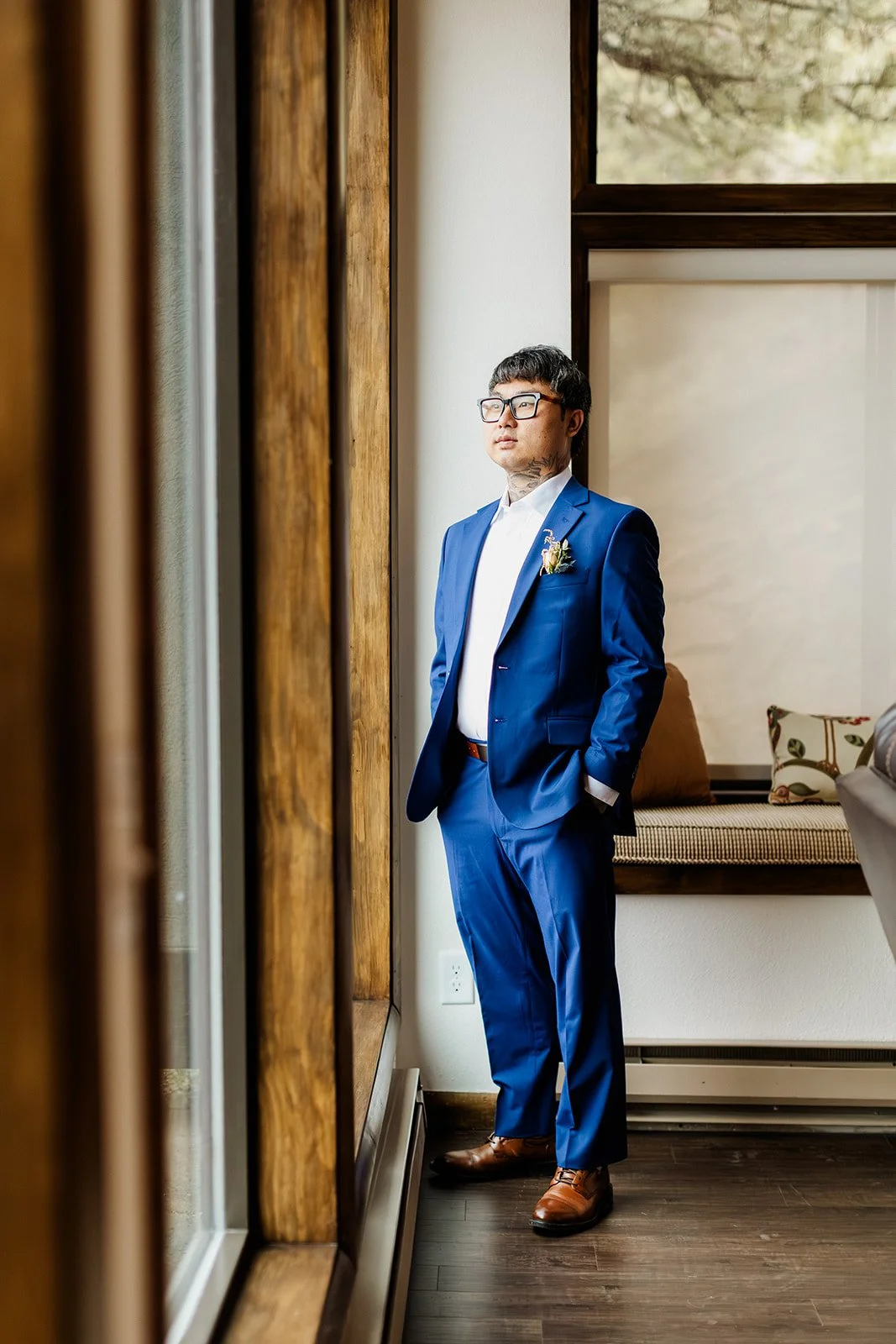 Groom in a blue suit looking out a cabin window