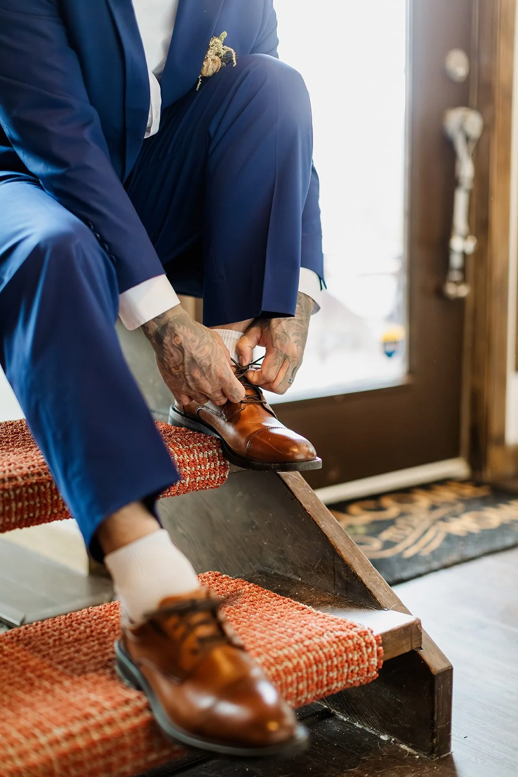 Close up of the groom tying his brown leather shoes