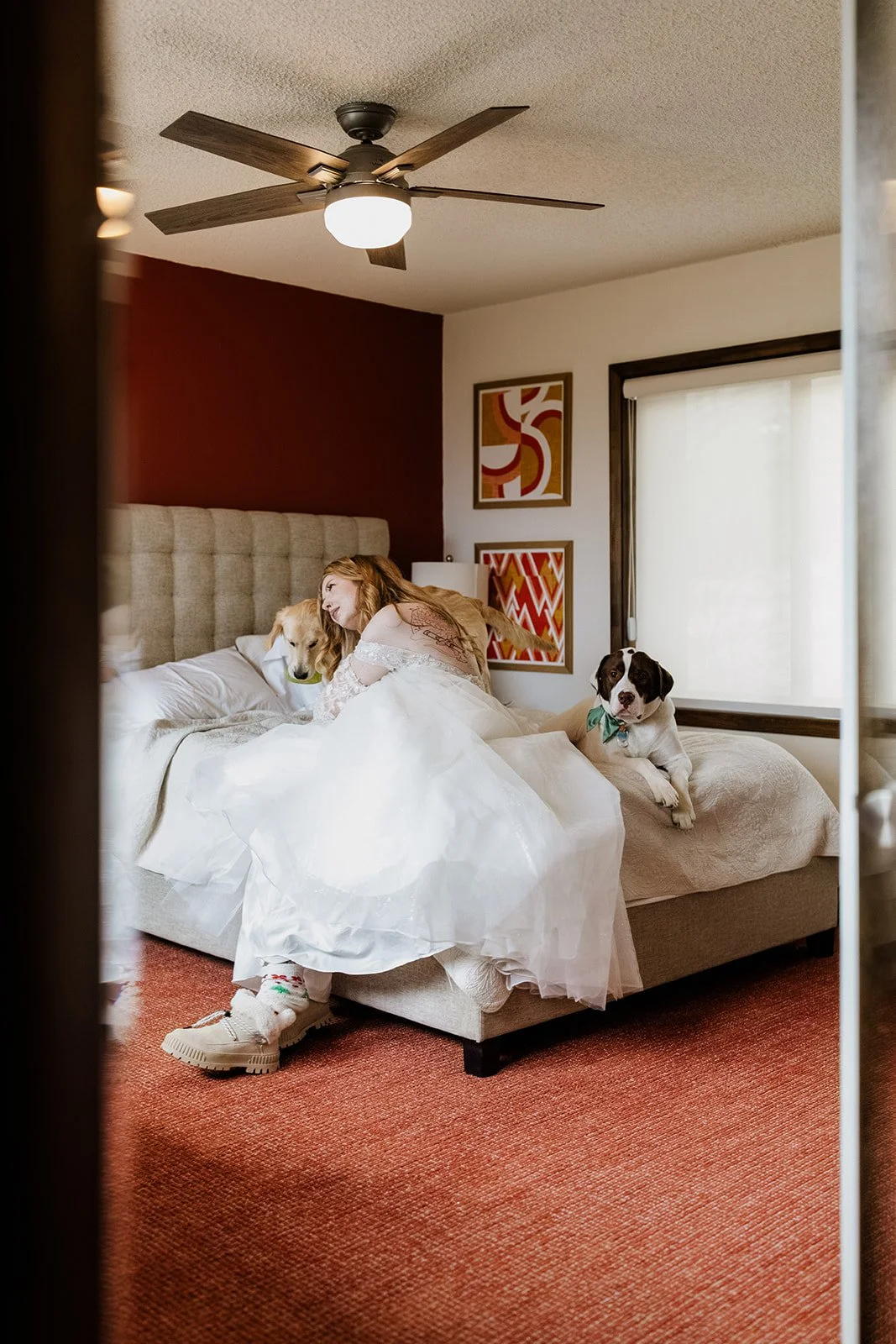 Bride sitting on the bed in her wedding dress with her two dogs