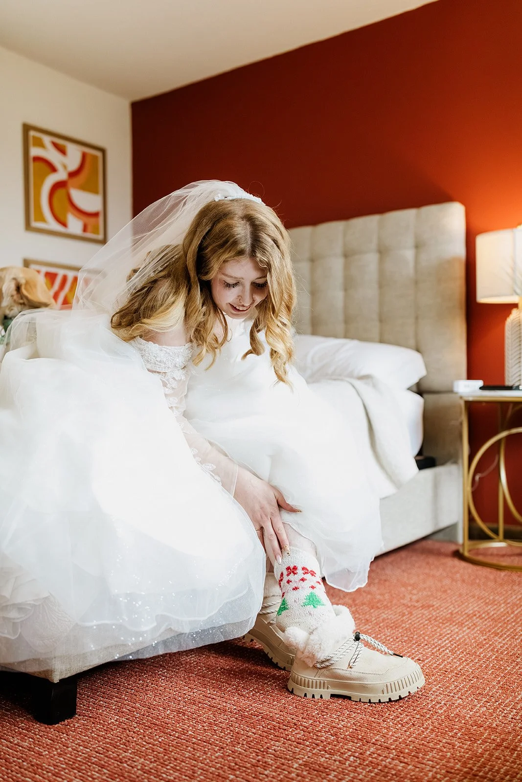 Bride pulling on white boots over red and green patterned socks