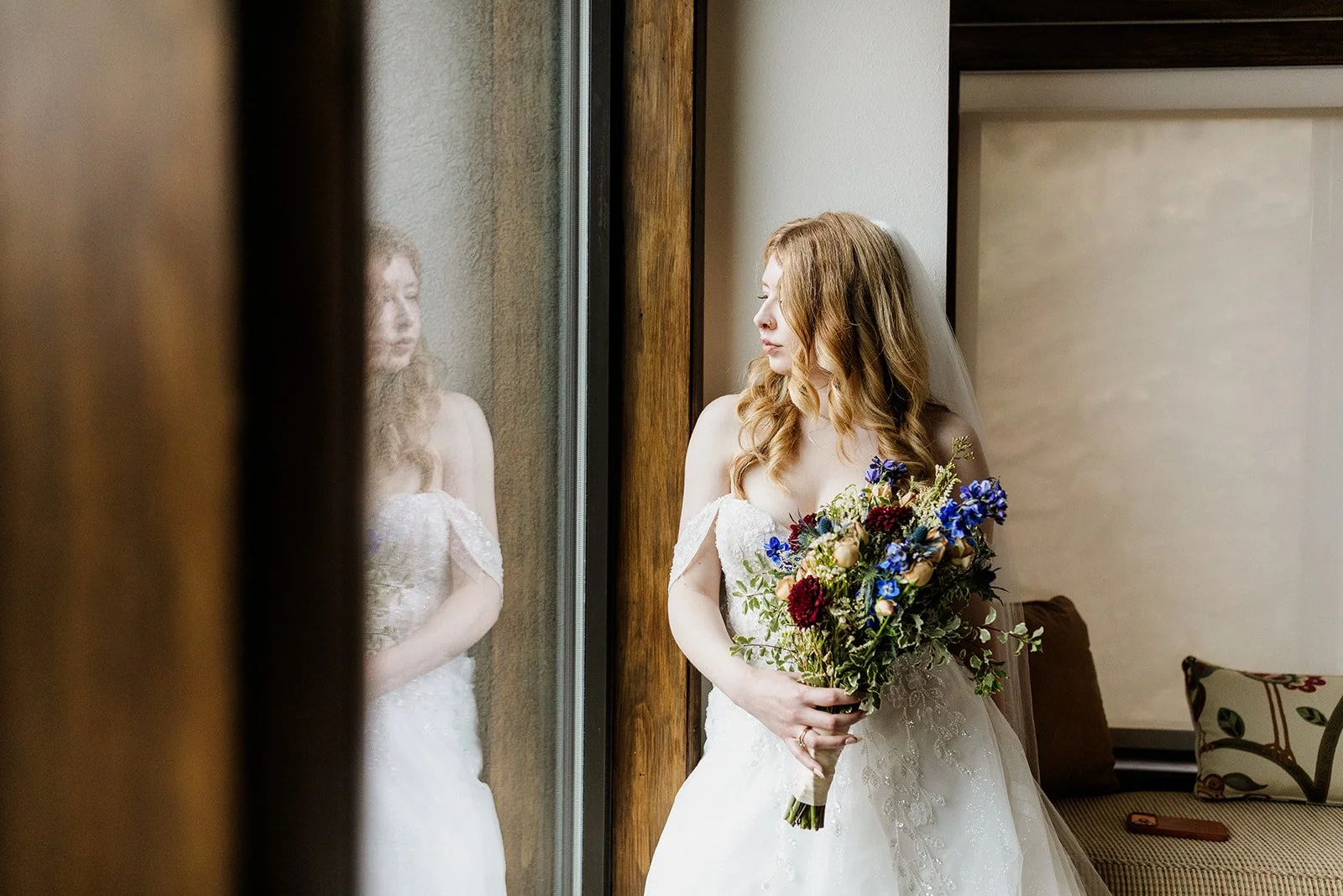 Bride looking out the window with her reflection in the glass