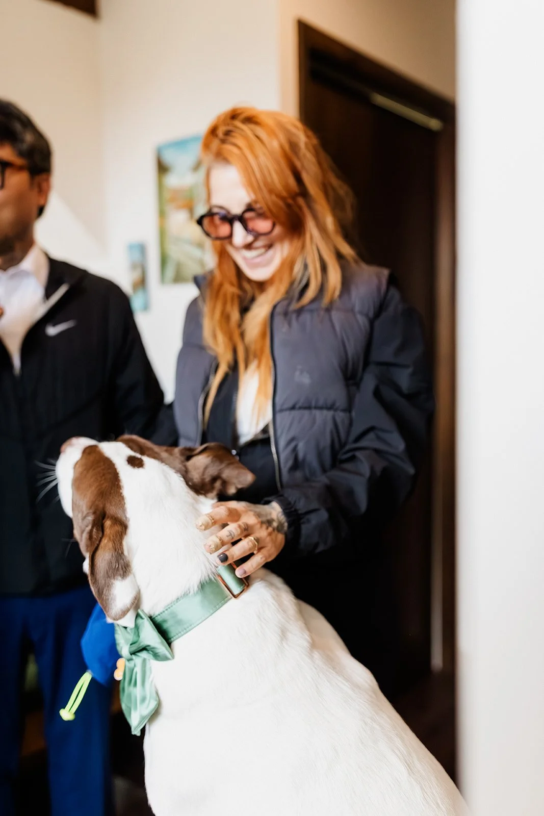 Friend laughing while petting the dog in a green bow tie