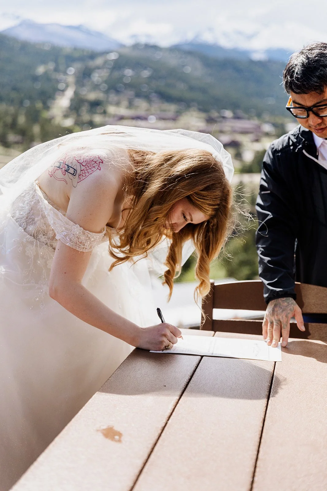 Bride signing the marriage license on a patio table in Estes Park