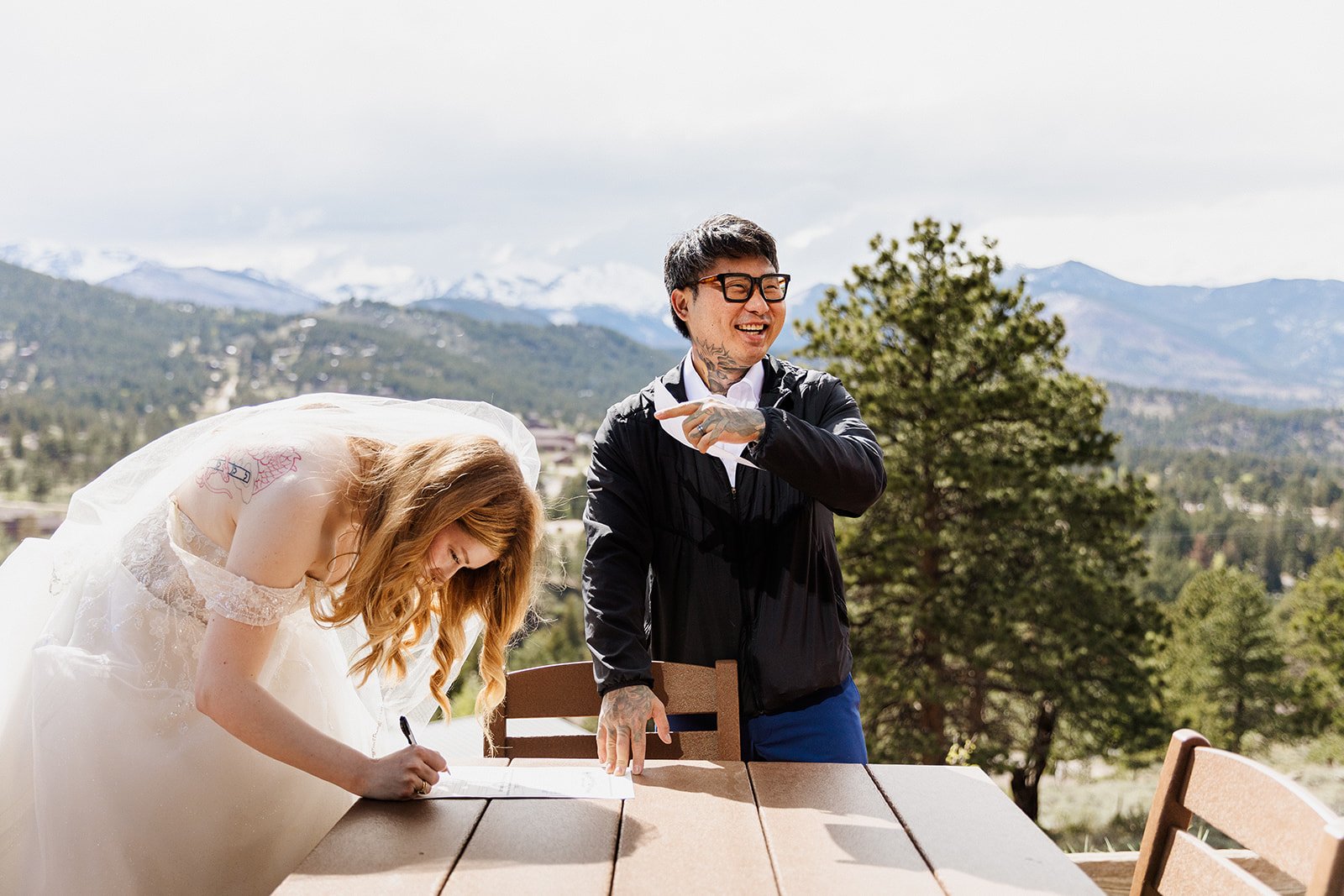Groom laughing while the bride signs their marriage license