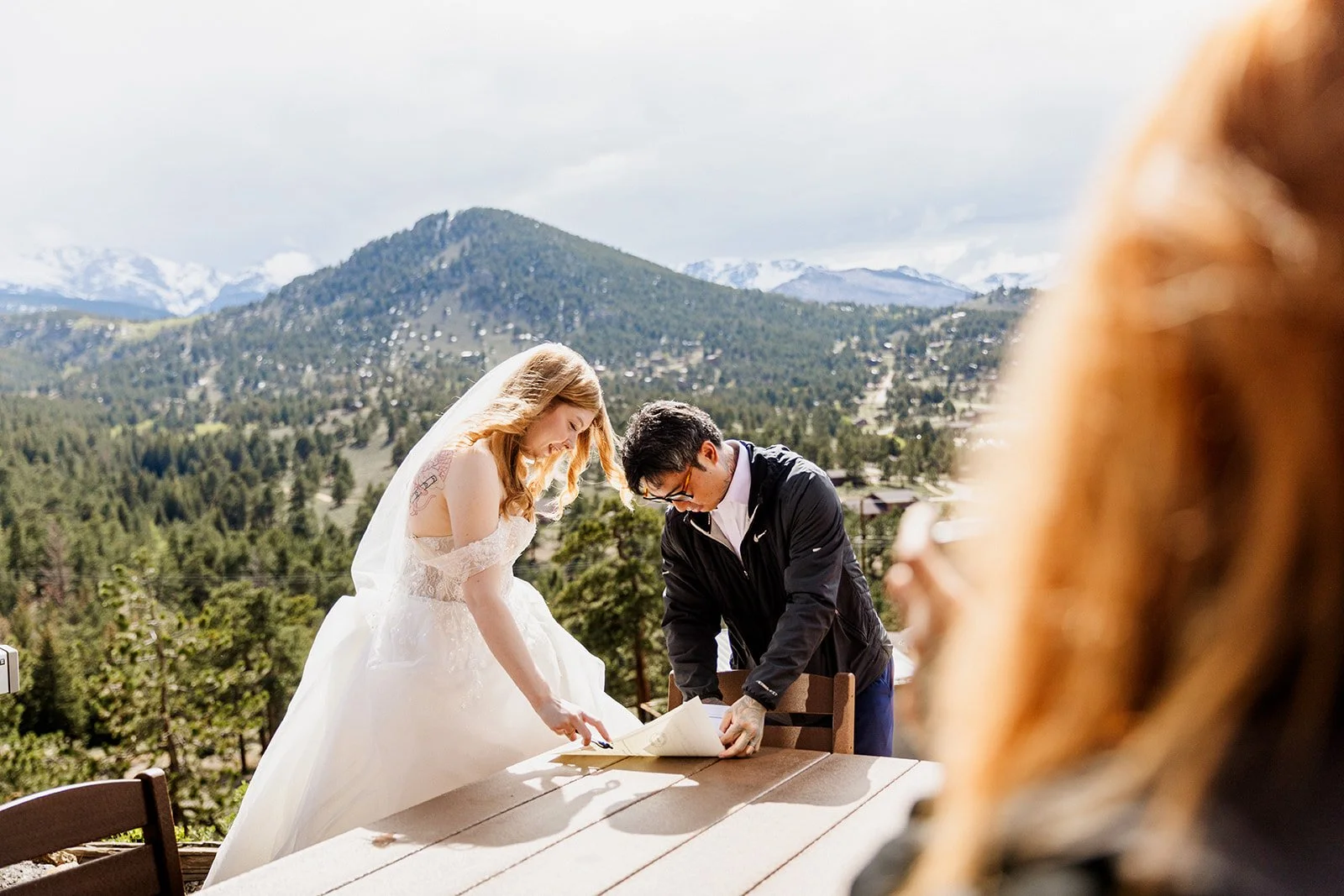 Couple signing their marriage license with mountain views behind them