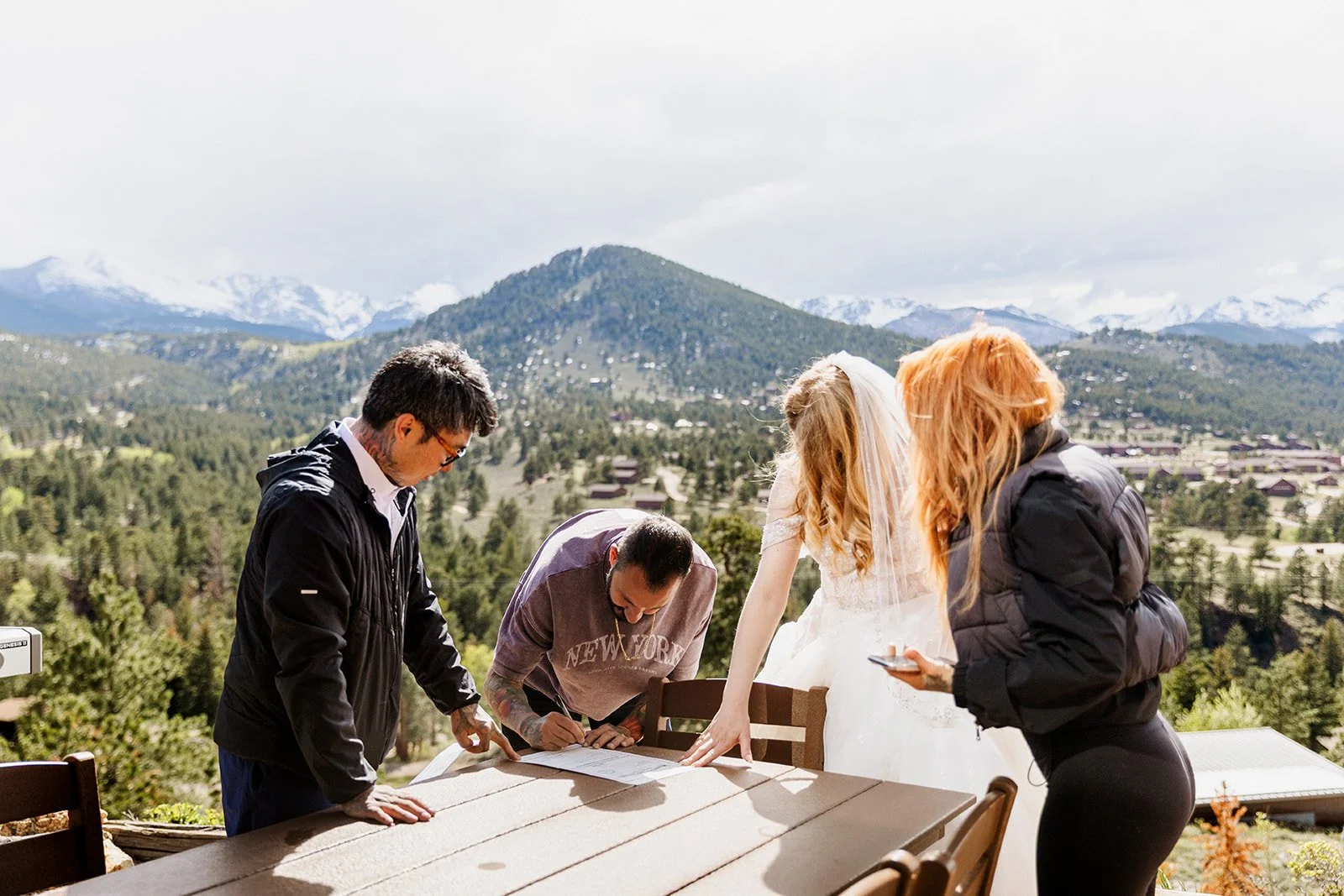 Couple and two friends gathered around the marriage license on a patio above Estes Park