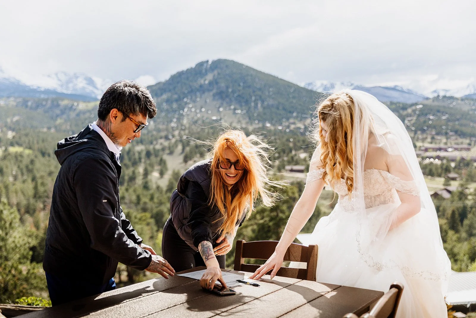 Friend signing the marriage license as a witness while the couple looks on