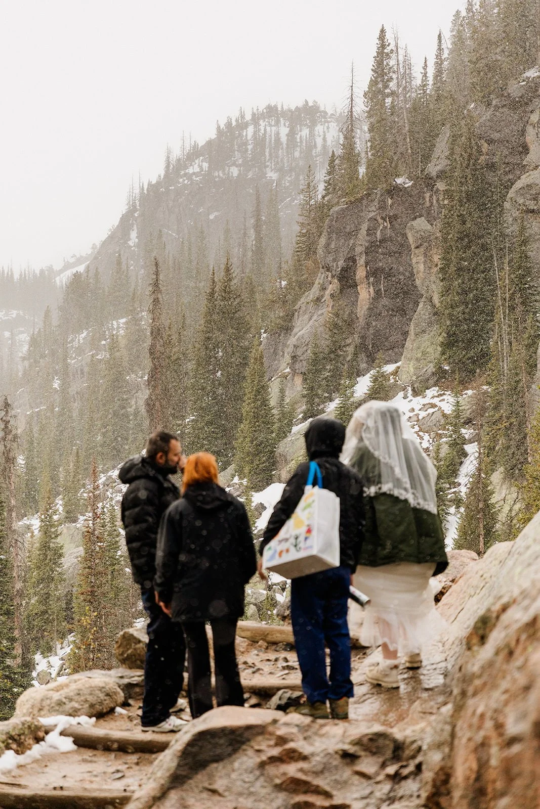 Couple and friends looking up at the cliffs through falling snow