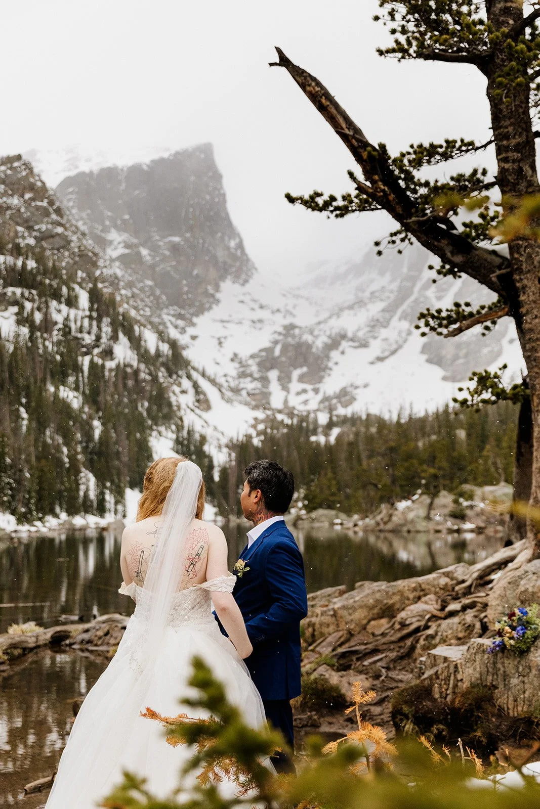 Couple standing at the edge of Dream Lake looking up at Hallett Peak