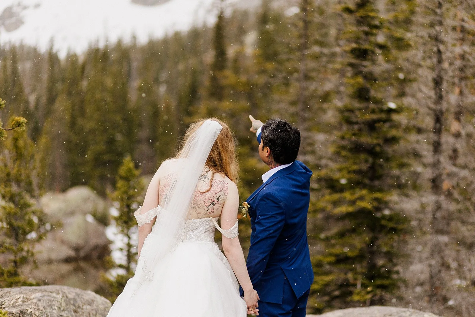 Groom pointing something out to the bride with light snow falling